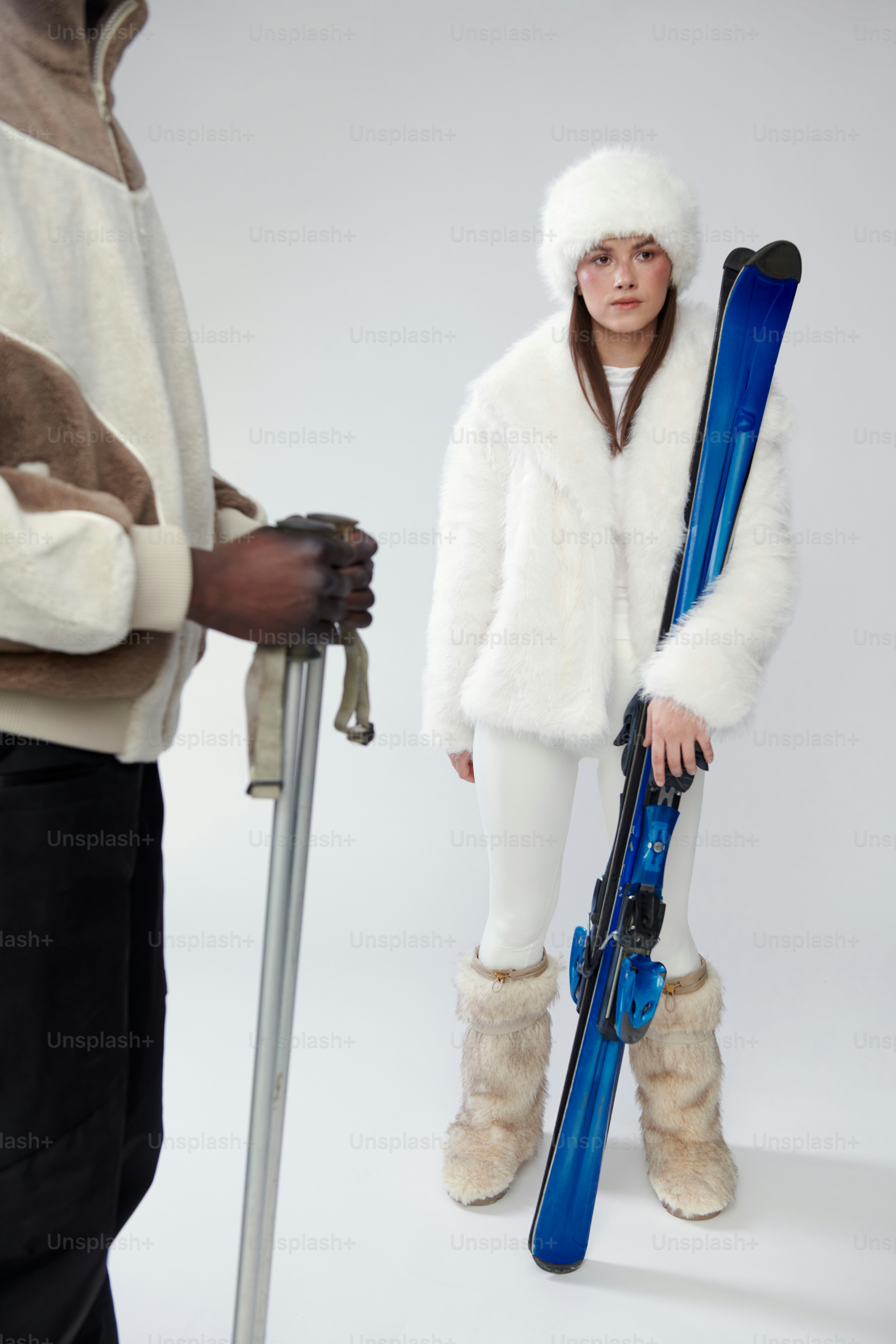 冬用スキーウェアを着た二人の人物がスキーとポールを持った