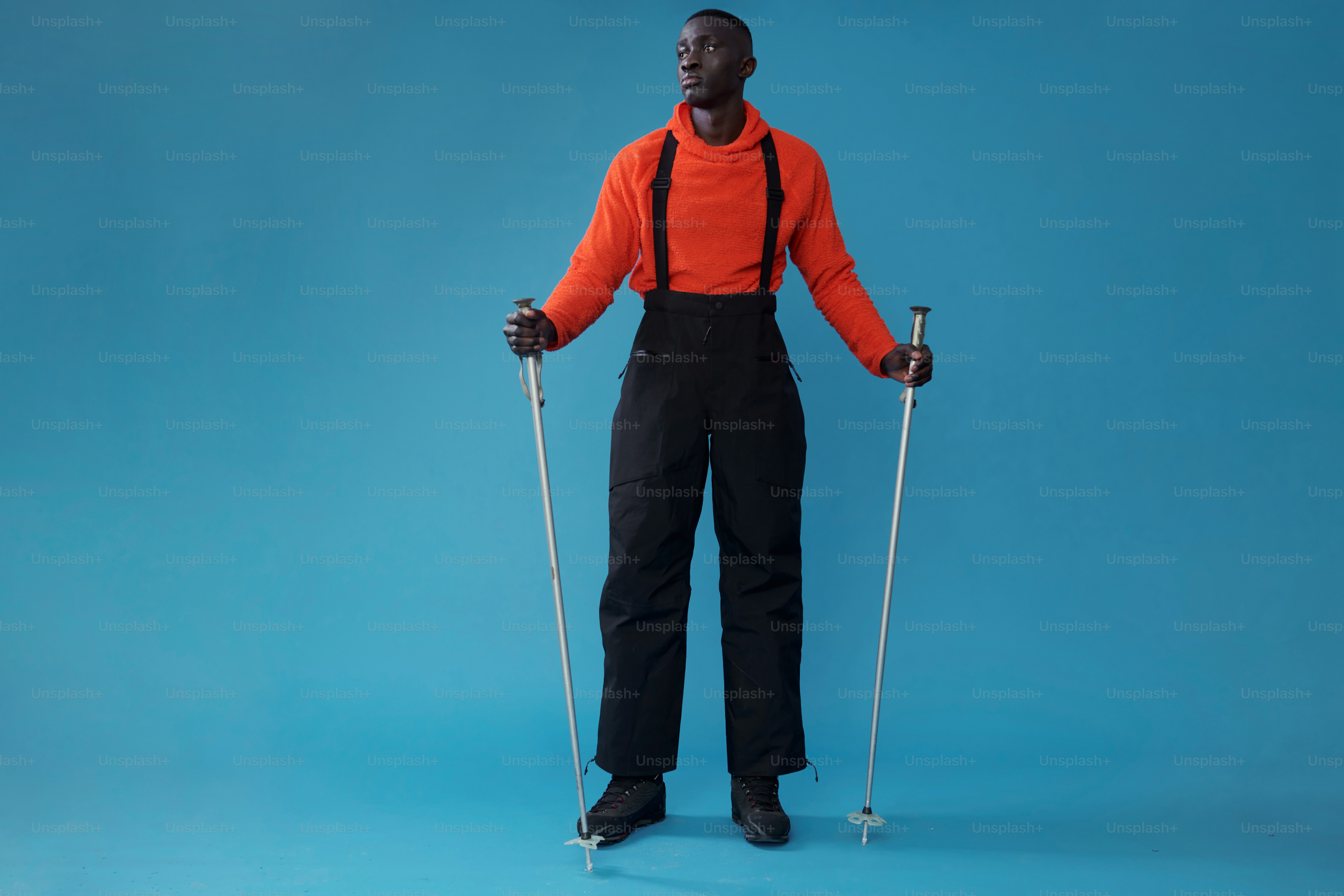 青い背景にスキーポールを持つスキーウェアの男性