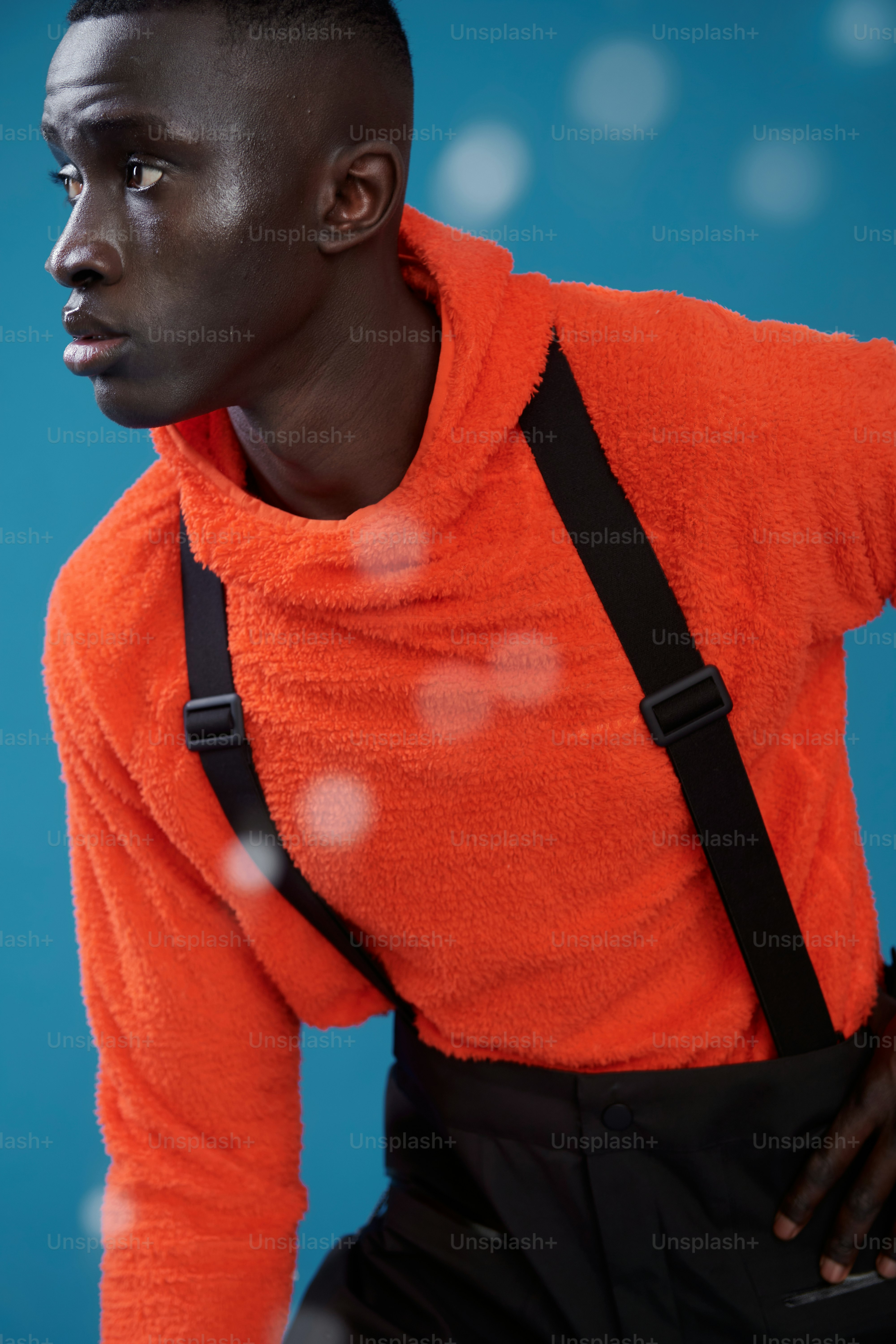 オレンジ色のセーターに黒いサスペンダーの男性