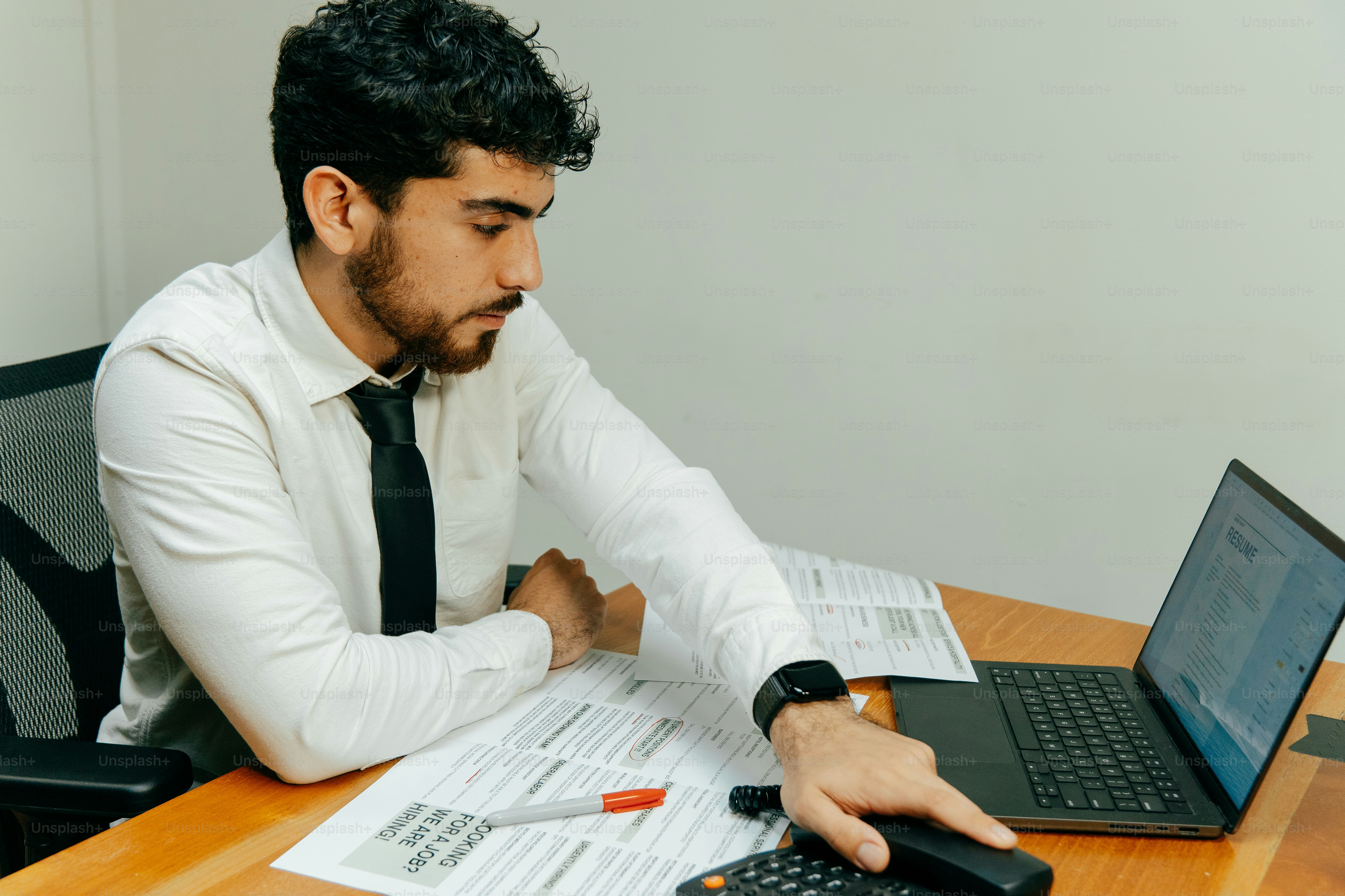 Man in a white shirt and tie using a calculator.