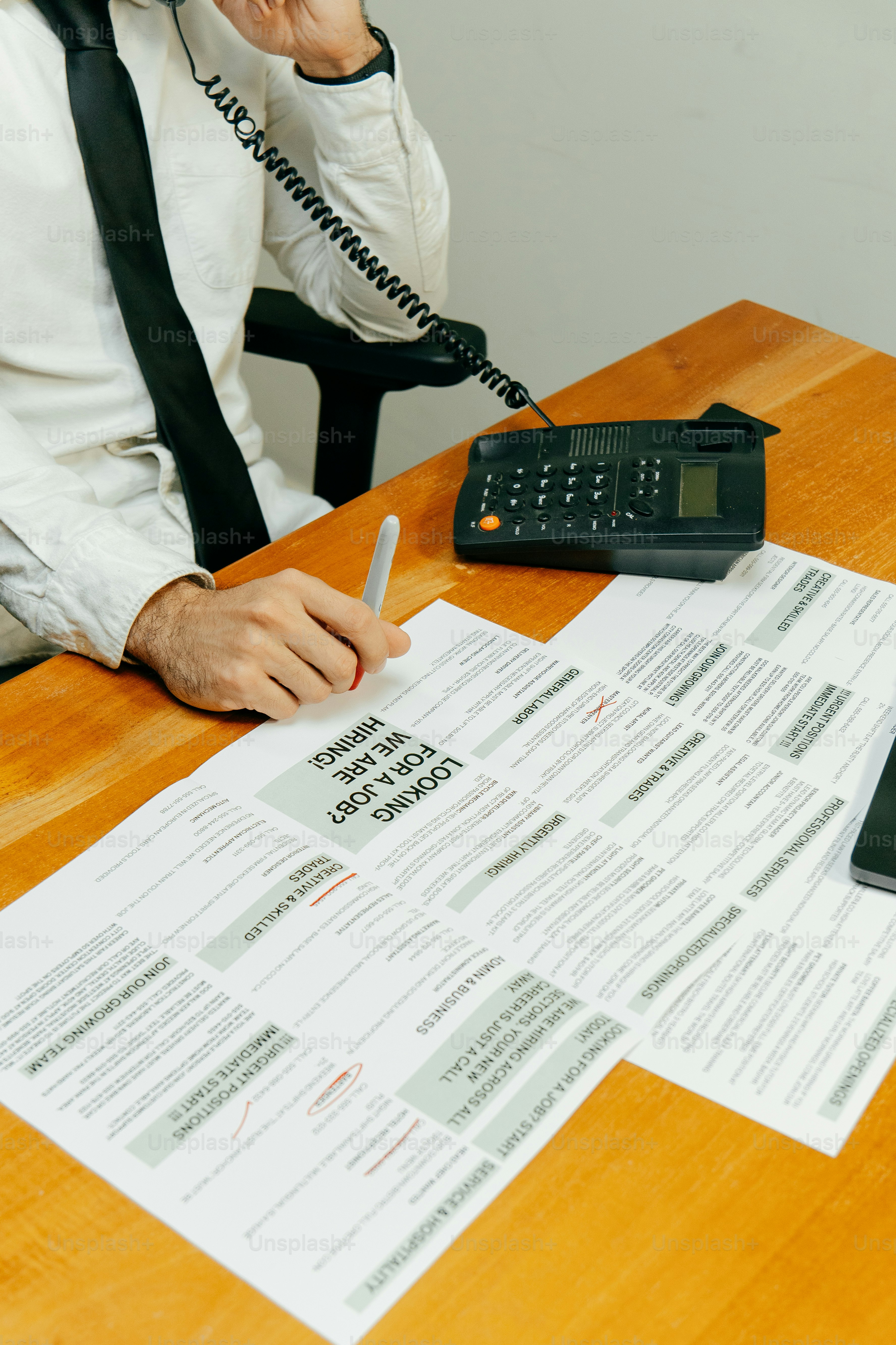Pria di telepon dengan daftar pekerjaan di meja