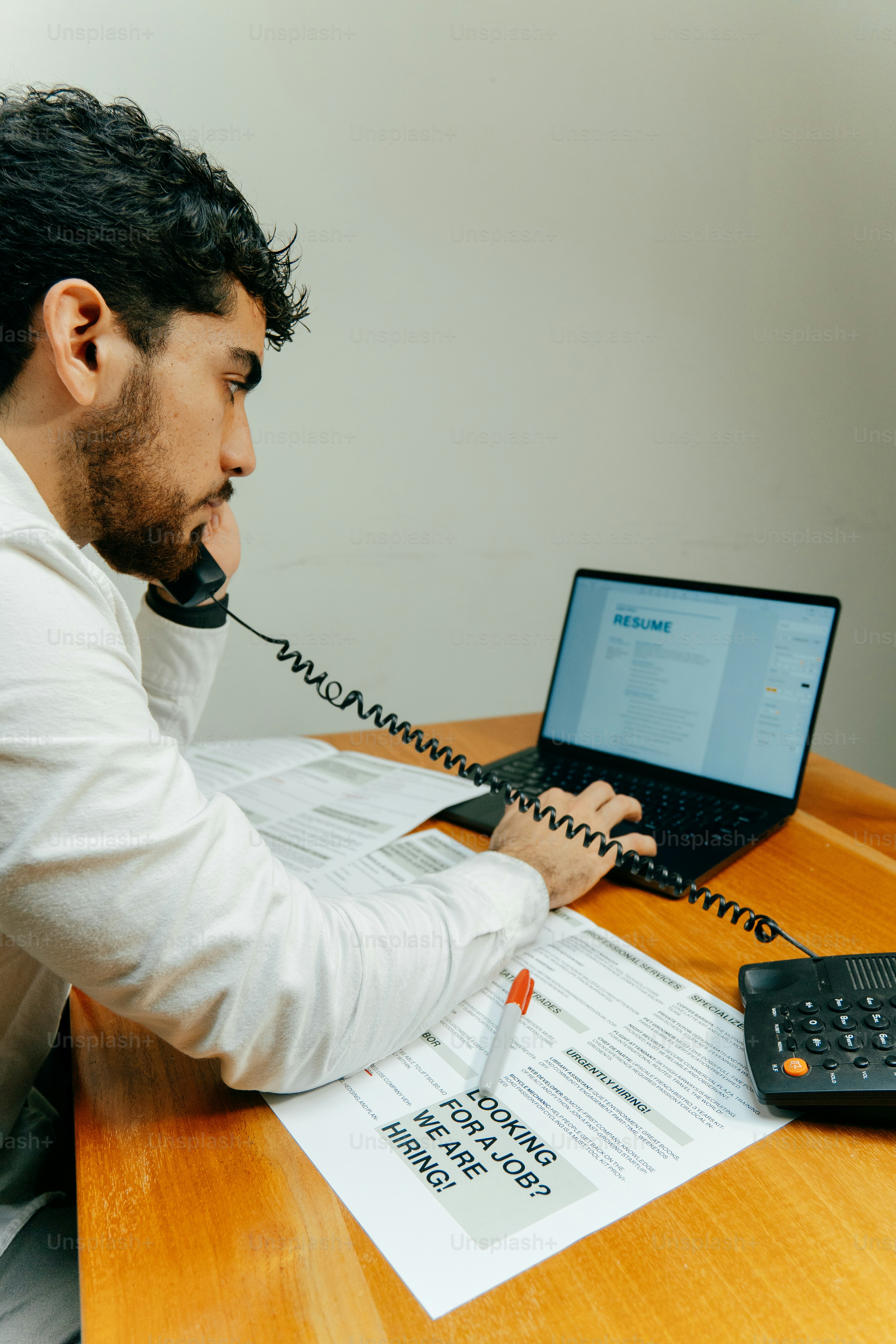 Man on phone near laptop and job application.