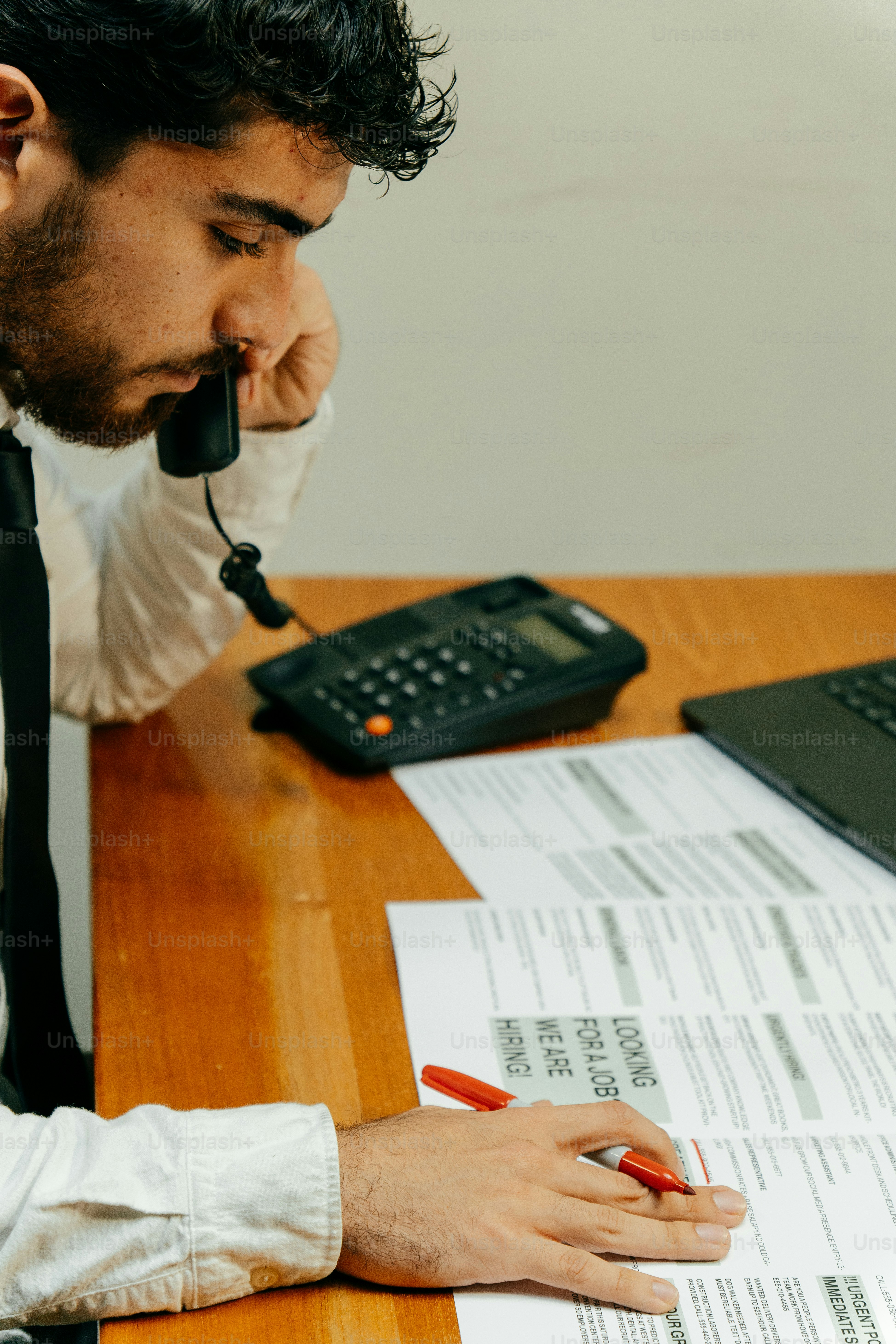 Pria berjas berbicara di telepon dengan kertas