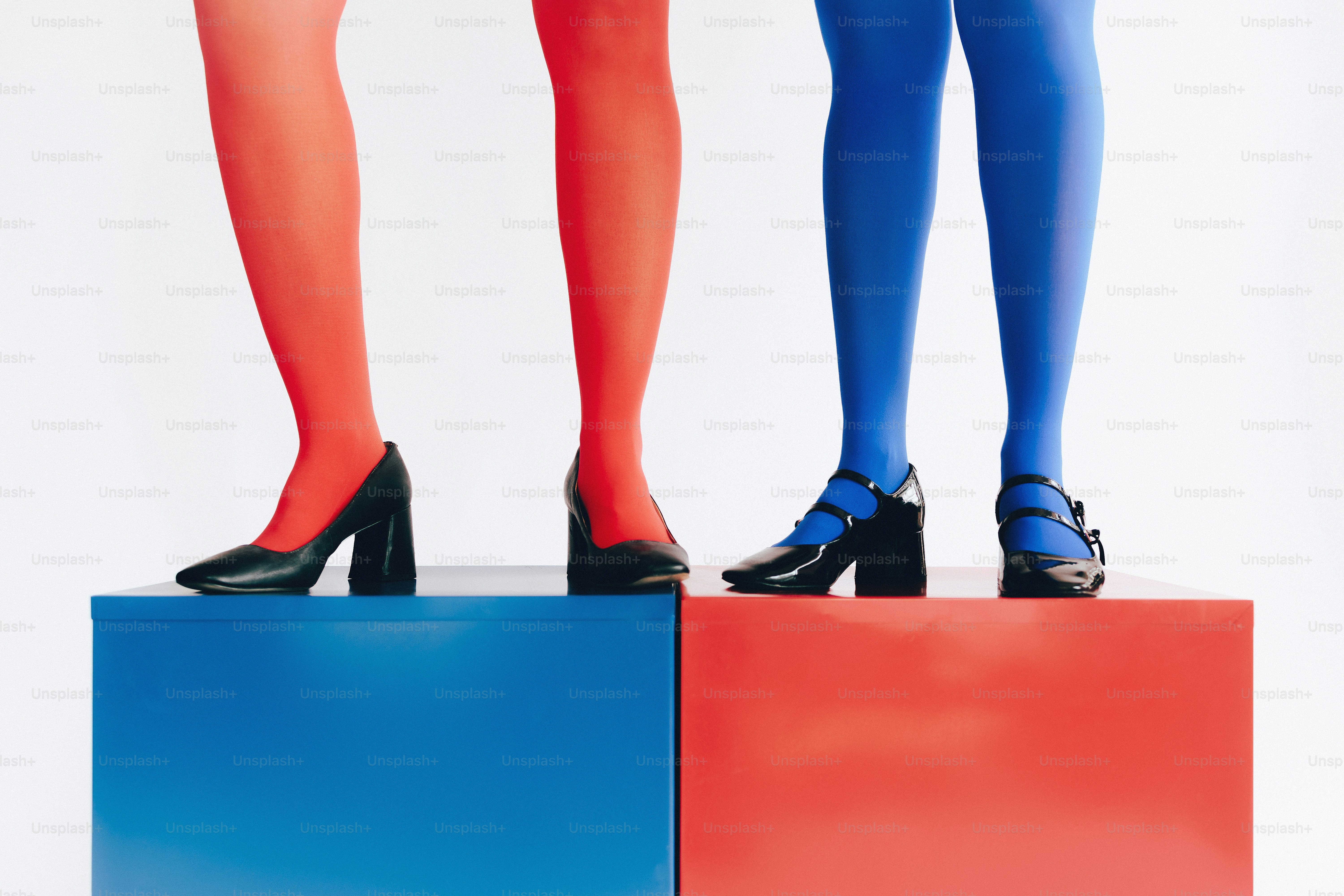 Zwei Paare von Beinen in farbigen Strumpfhosen und High Heels.