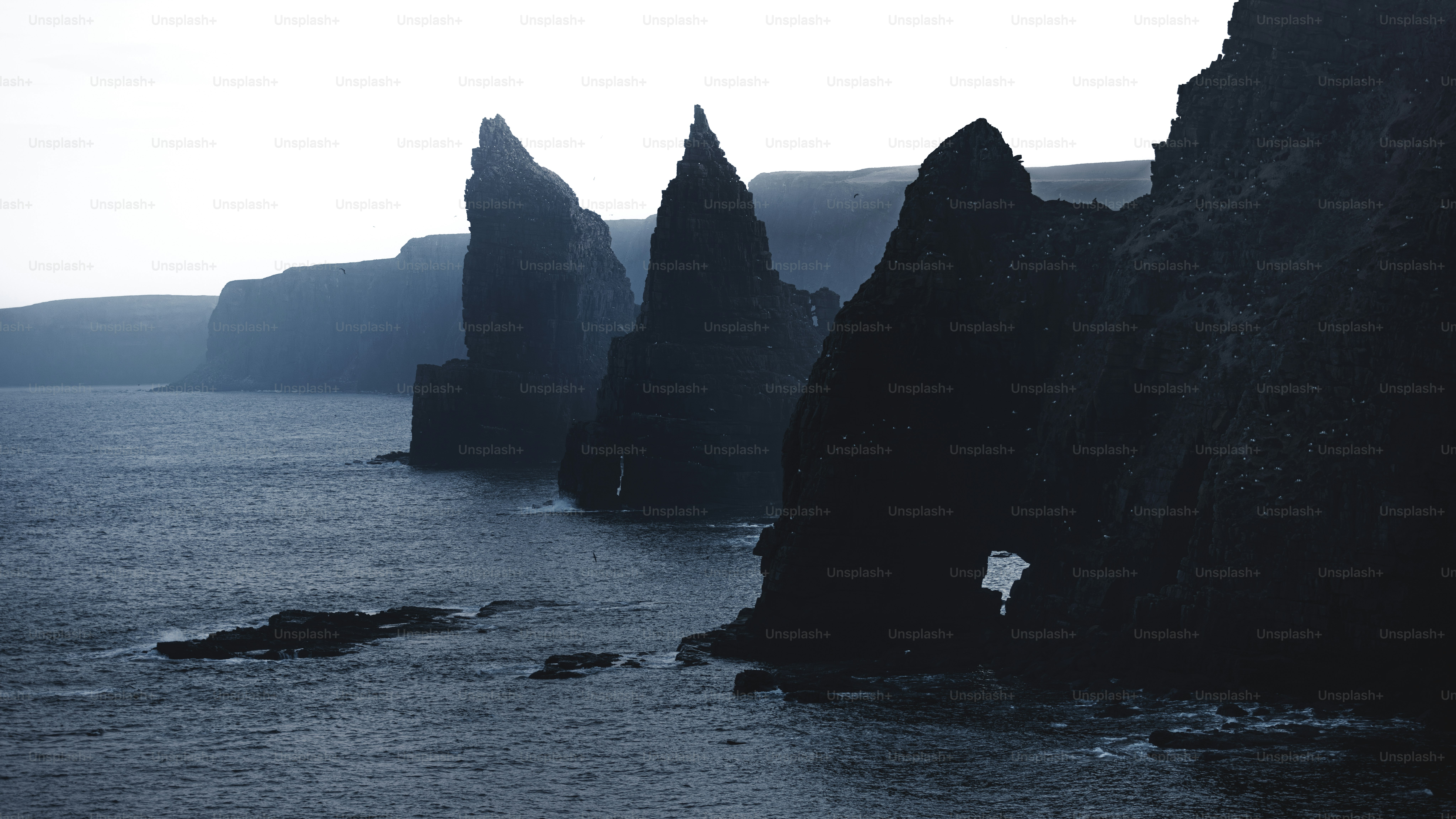 Jagged sea stacks rise from the dark ocean water.