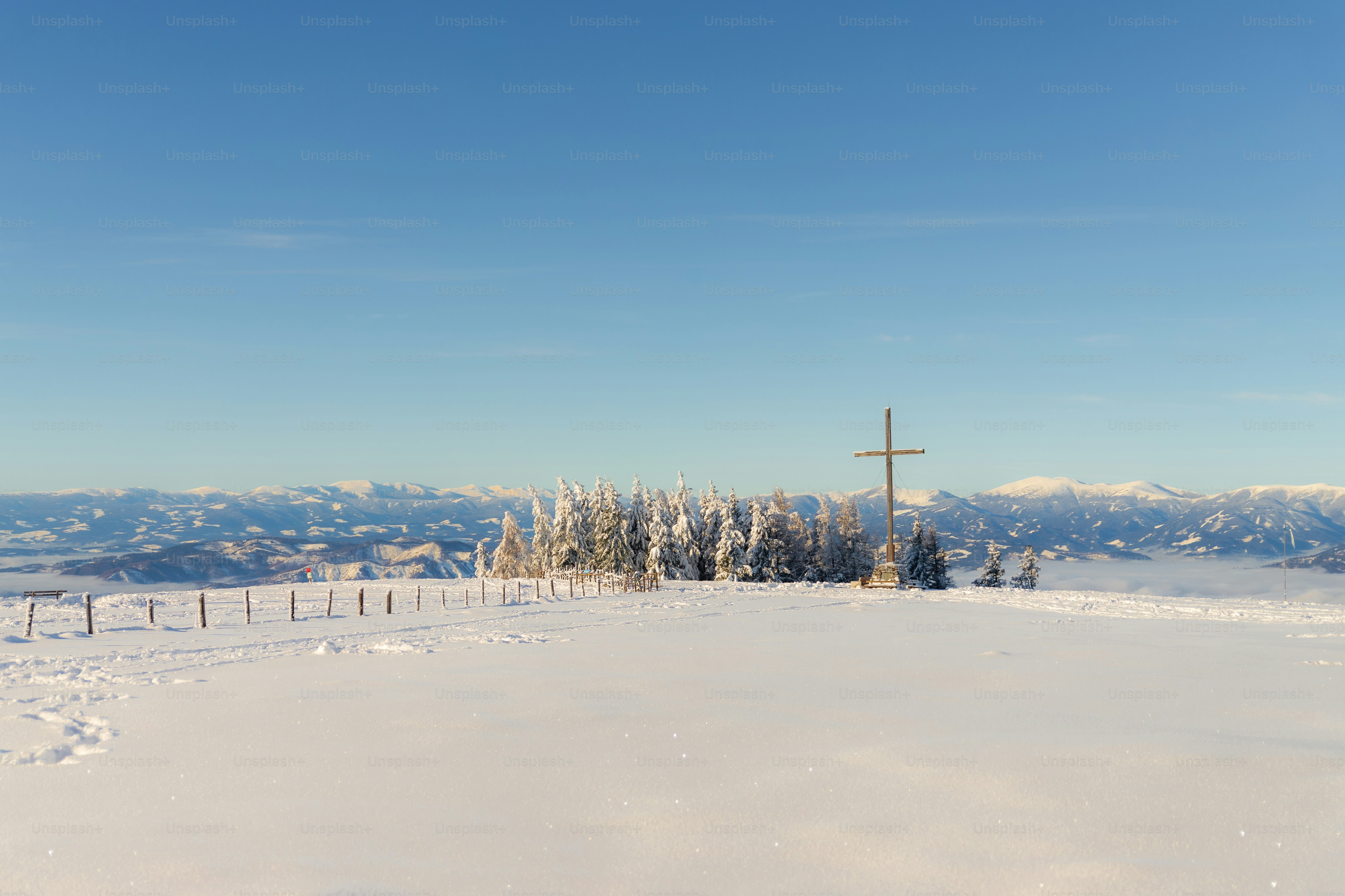Snowy mountain landscape with a cross and trees.