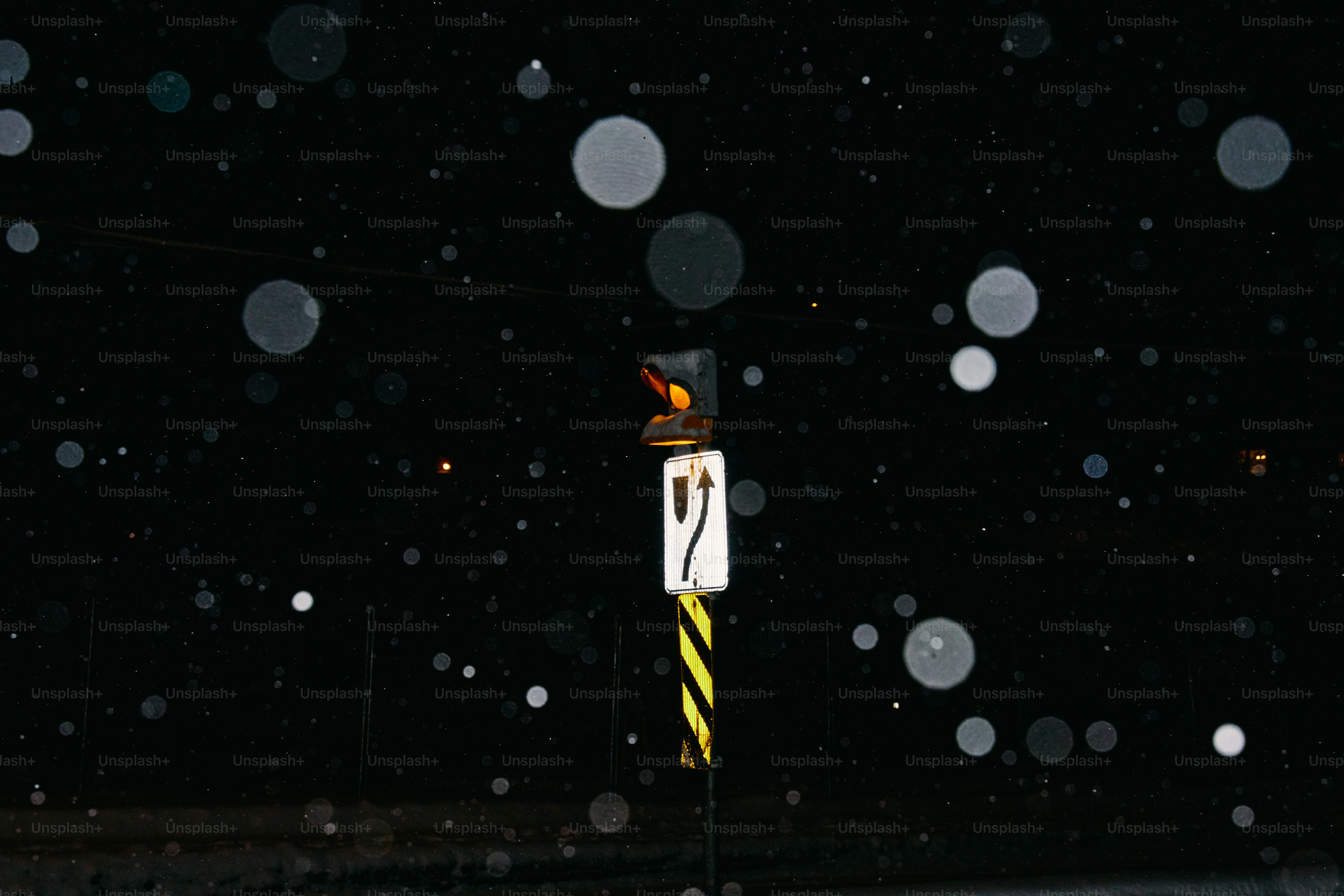 Traffic signal in falling snow at night.