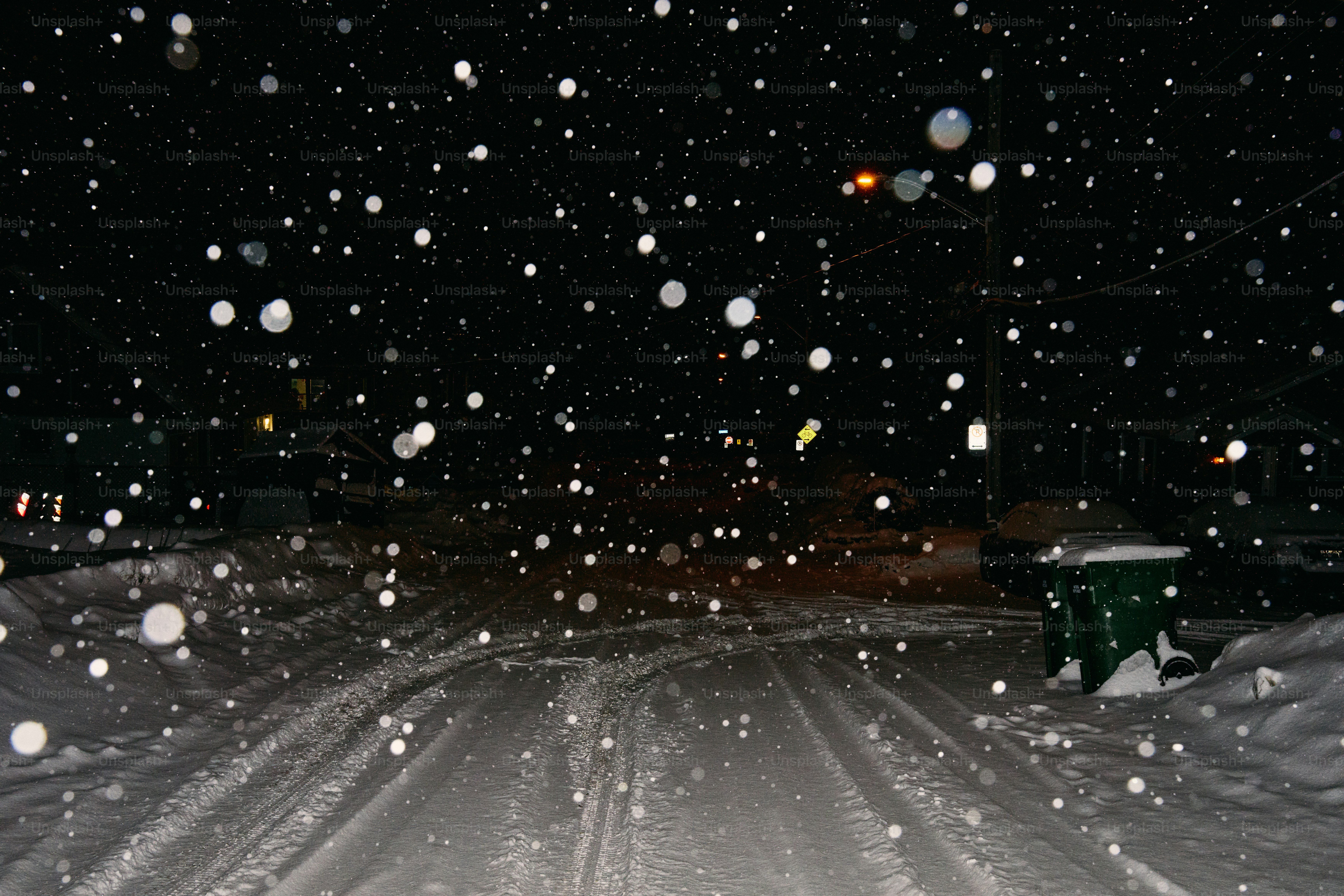Snow falling on a dark street at night.