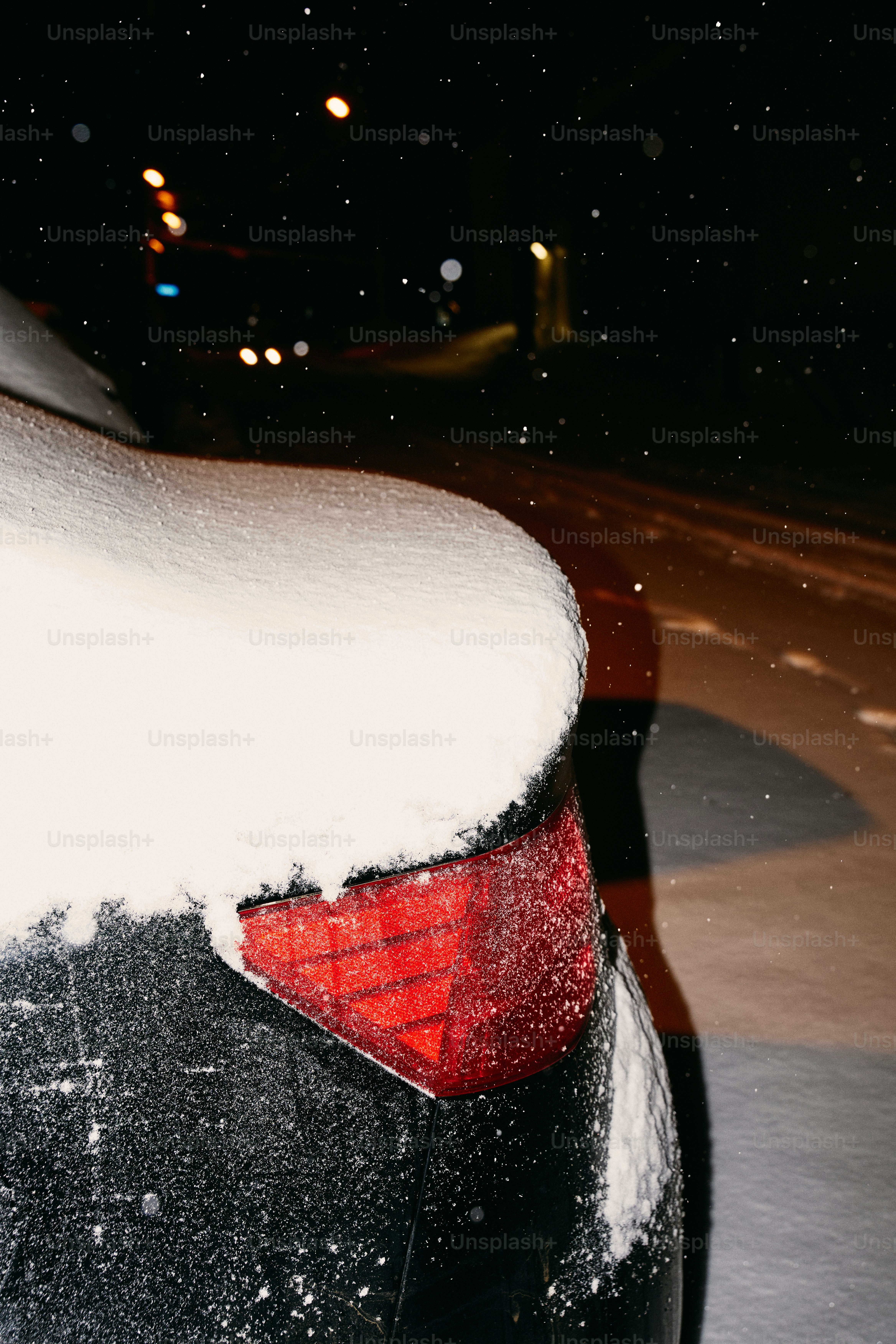 Car taillight covered in snow at night