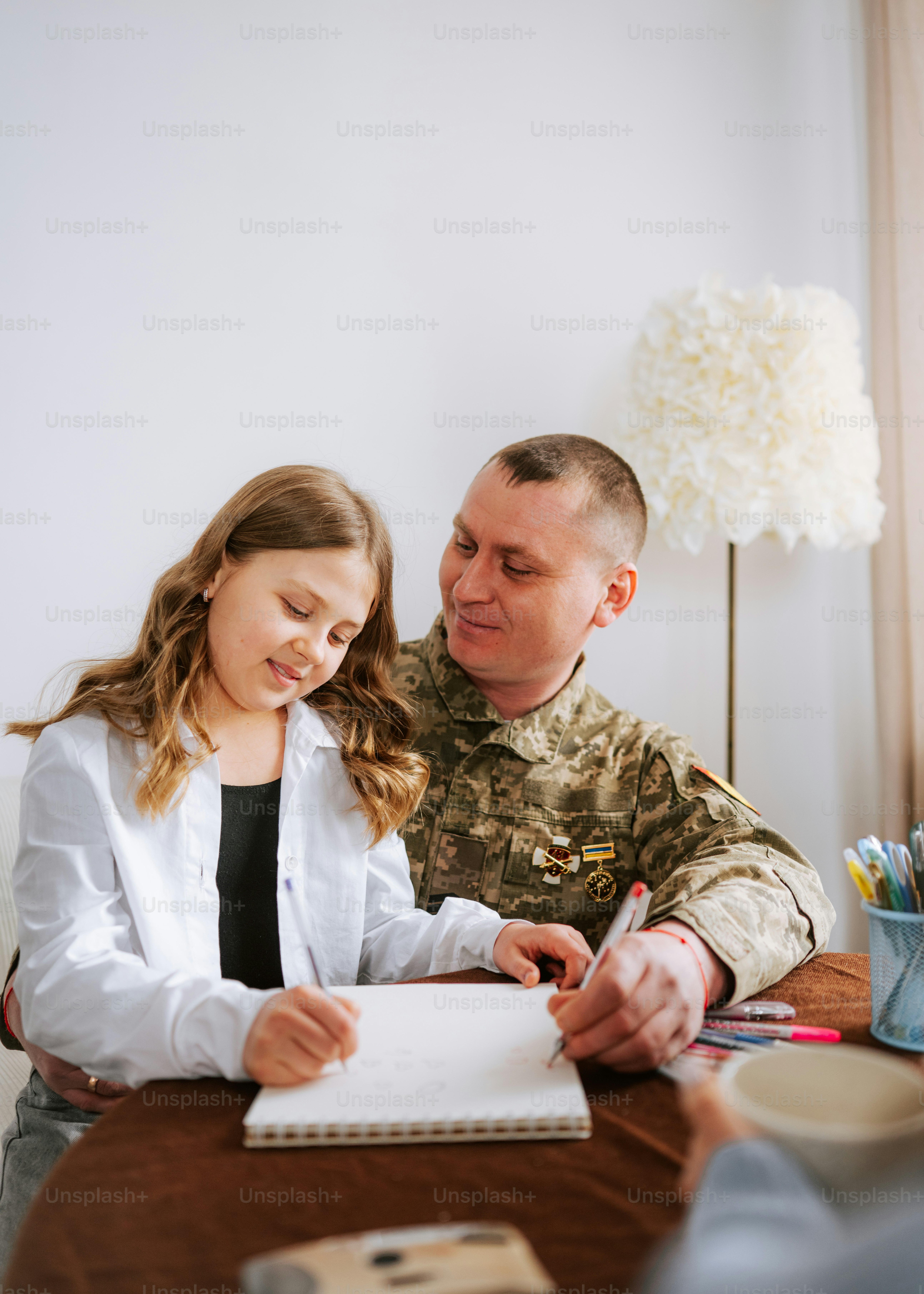 Un soldat aide sa fille à dessiner à la maison