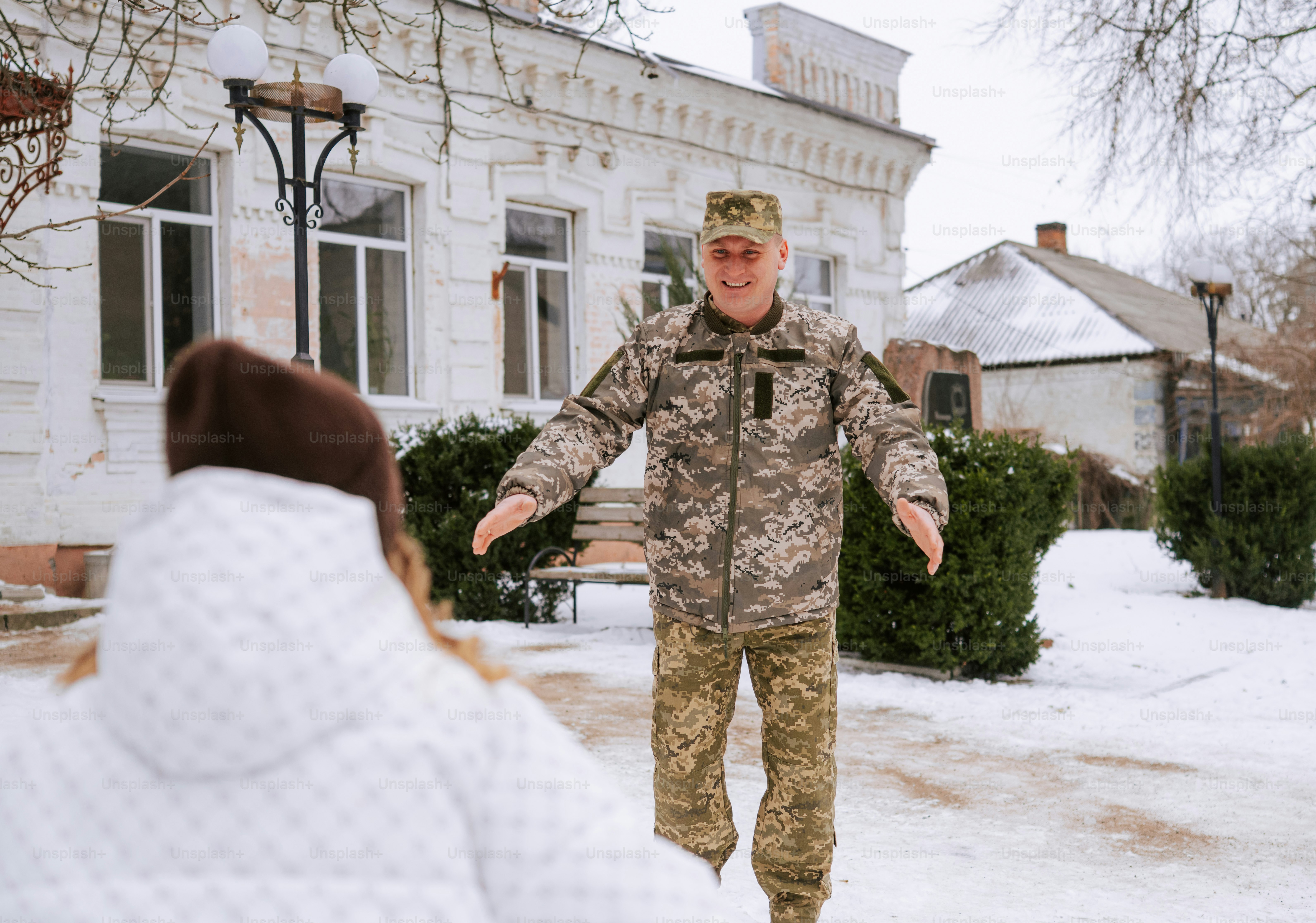 Soldado de uniforme camuflado abraça pessoa na neve