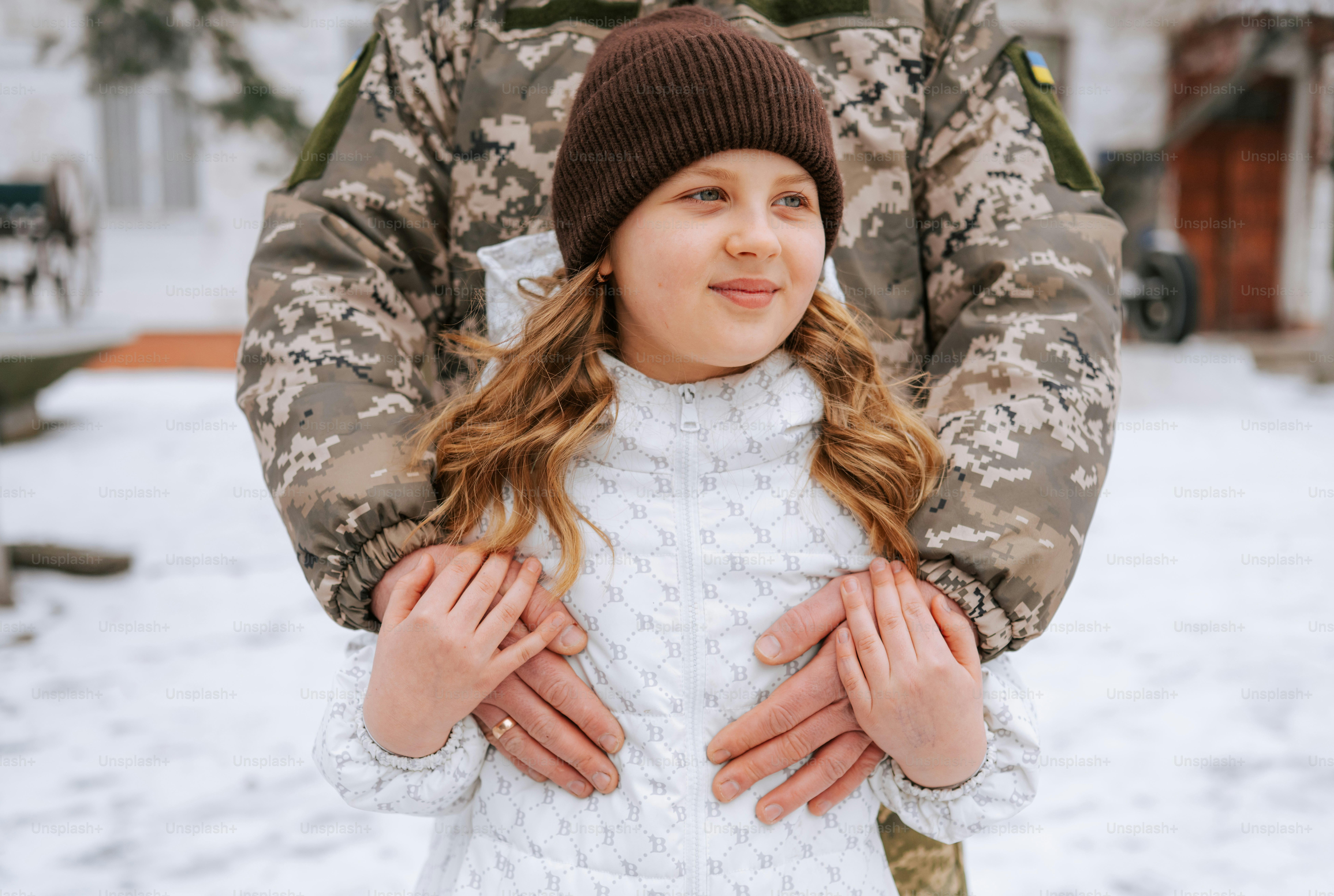 Un soldat serre une jeune fille dans les bras dans la neige.