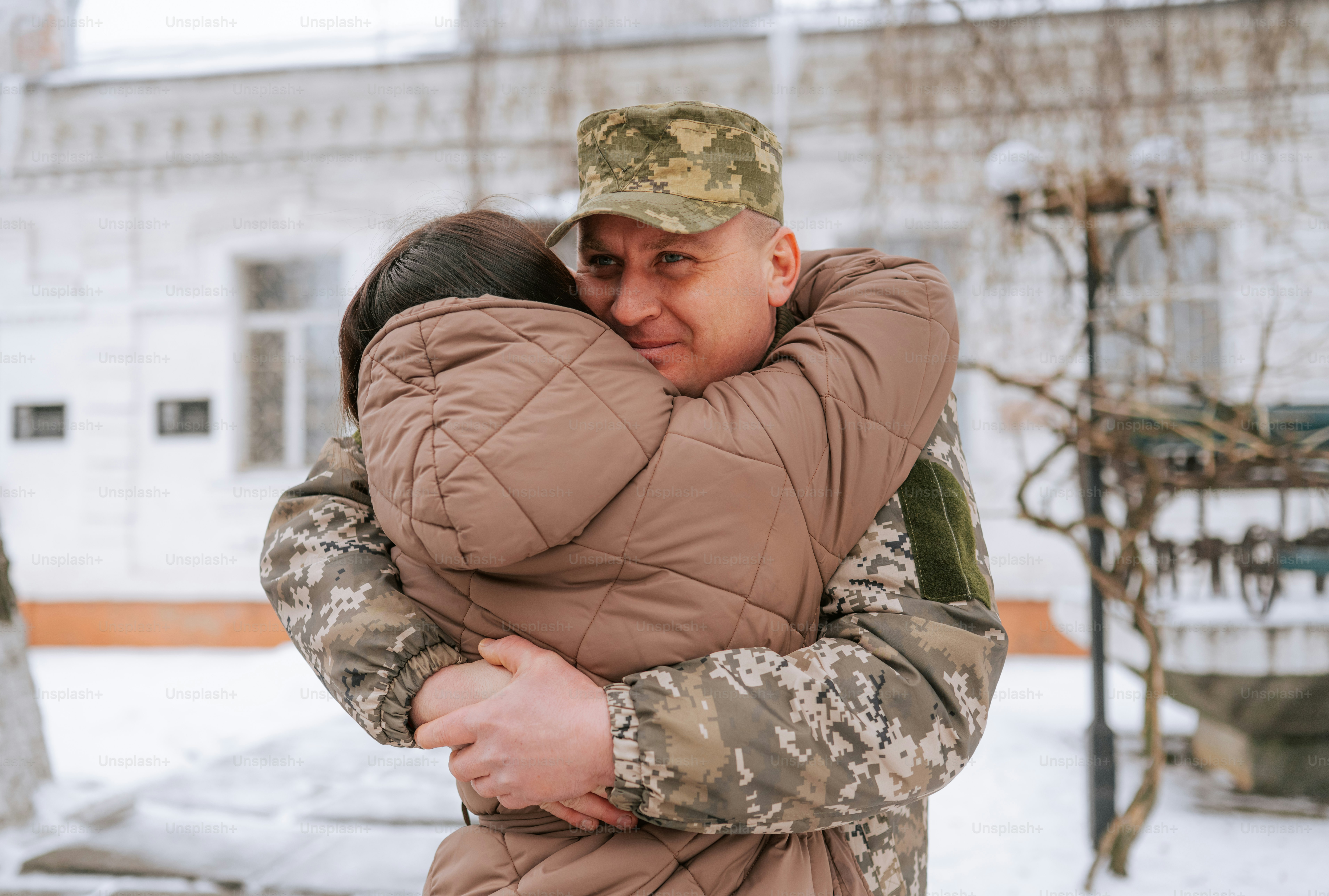 Soldat en uniforme serrant une personne dans ses bras en hiver