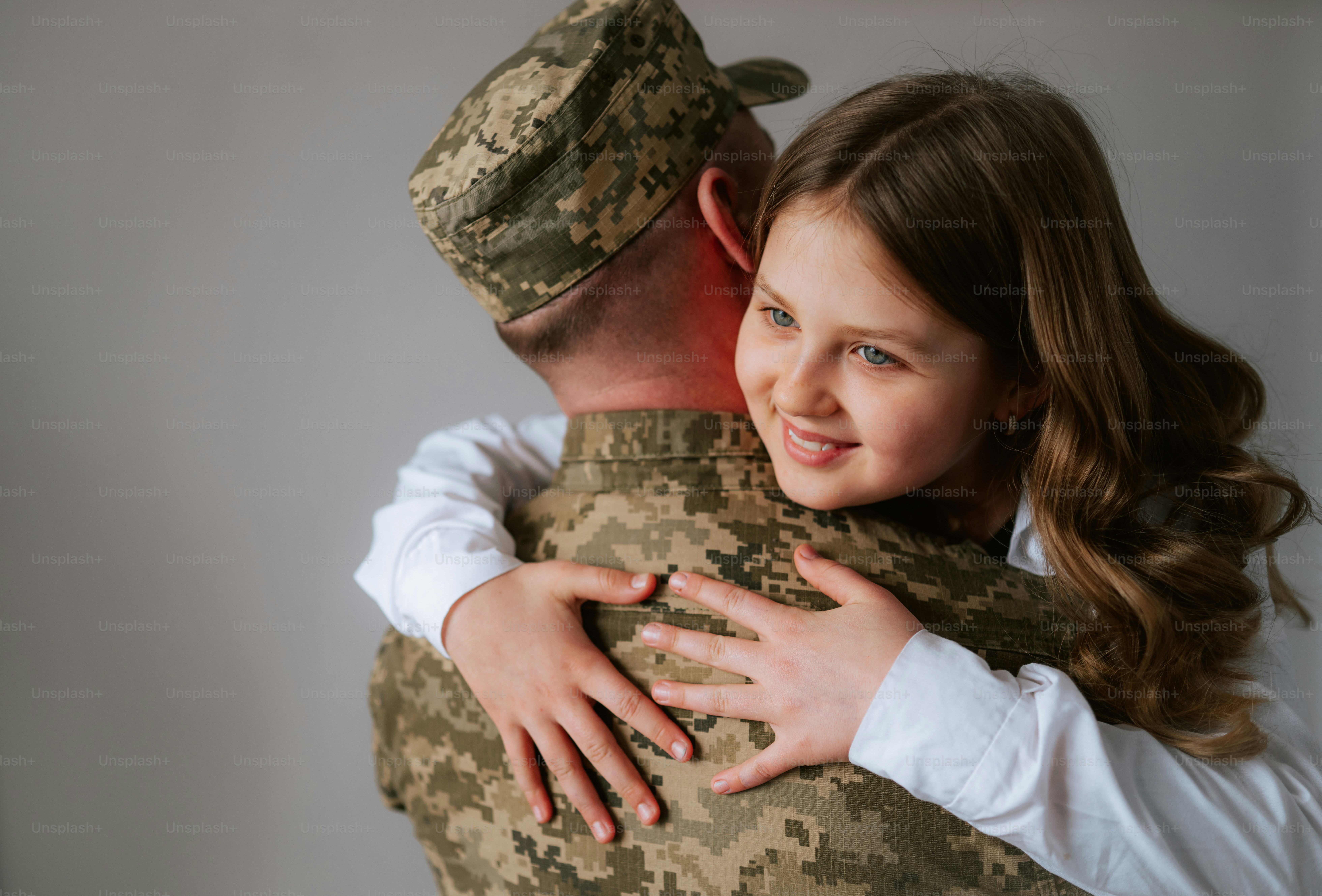 Une fille souriante serre un soldat en uniforme.