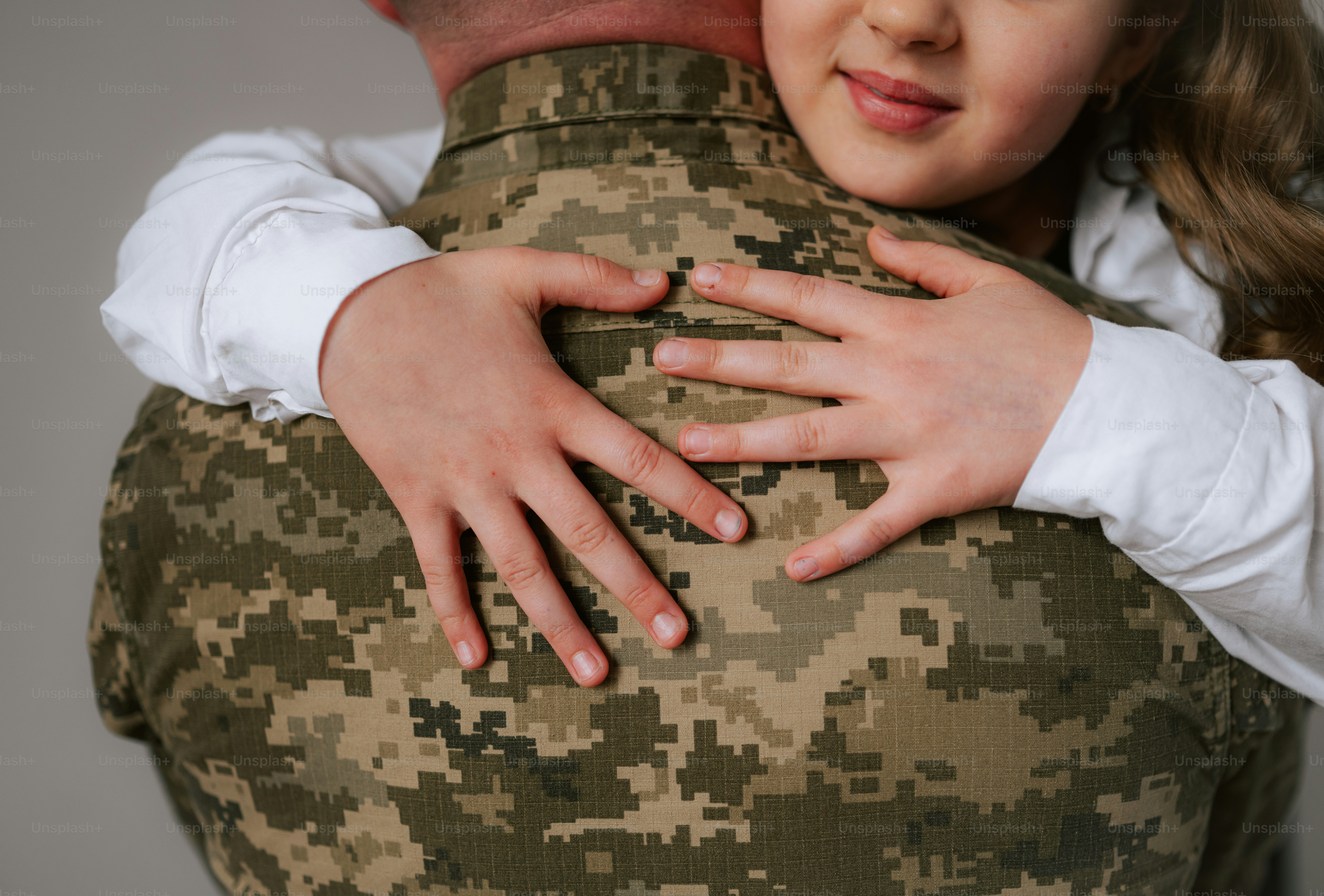 Un enfant serre un soldat en uniforme de camouflage.