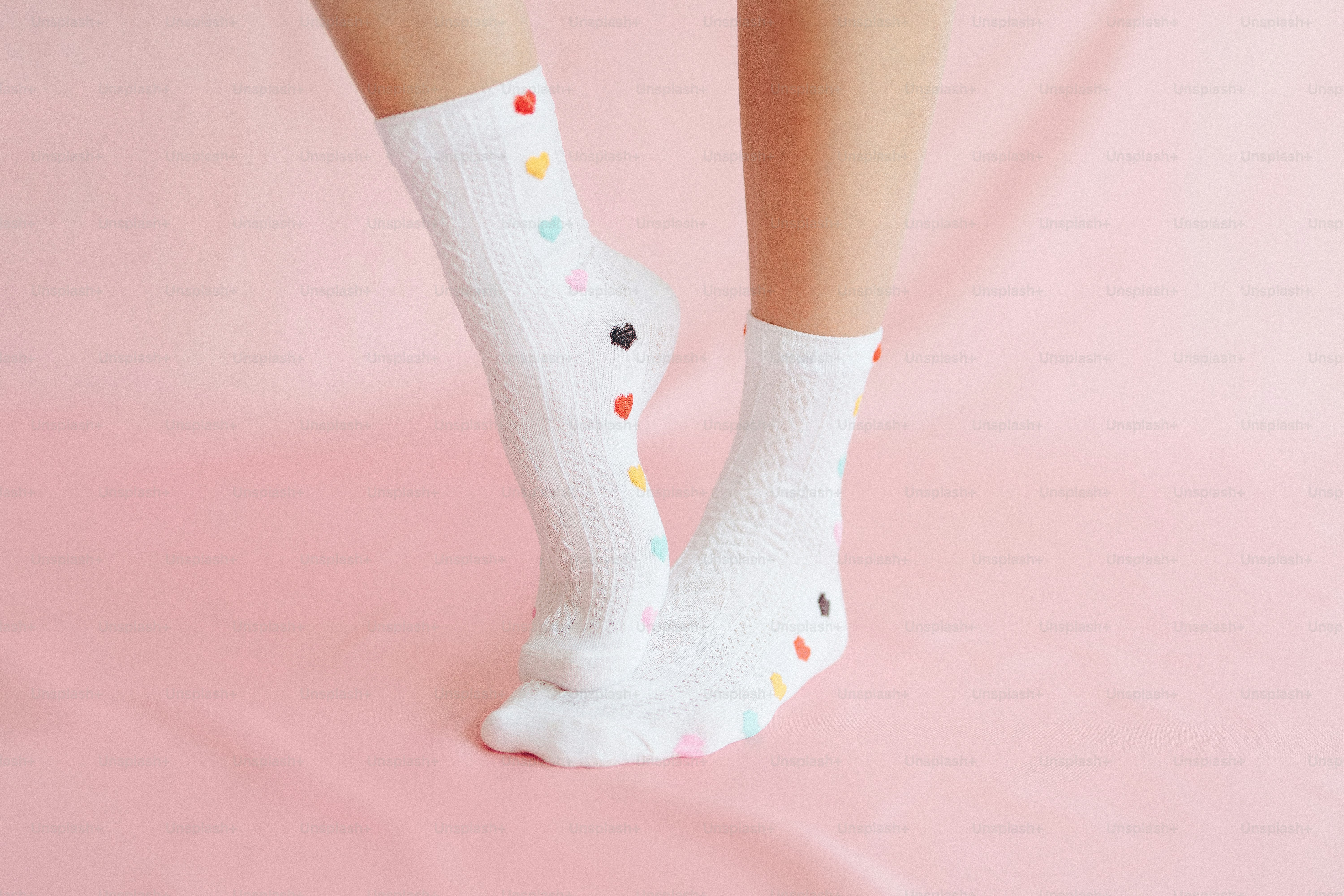 White socks with colorful heart patterns on pink background