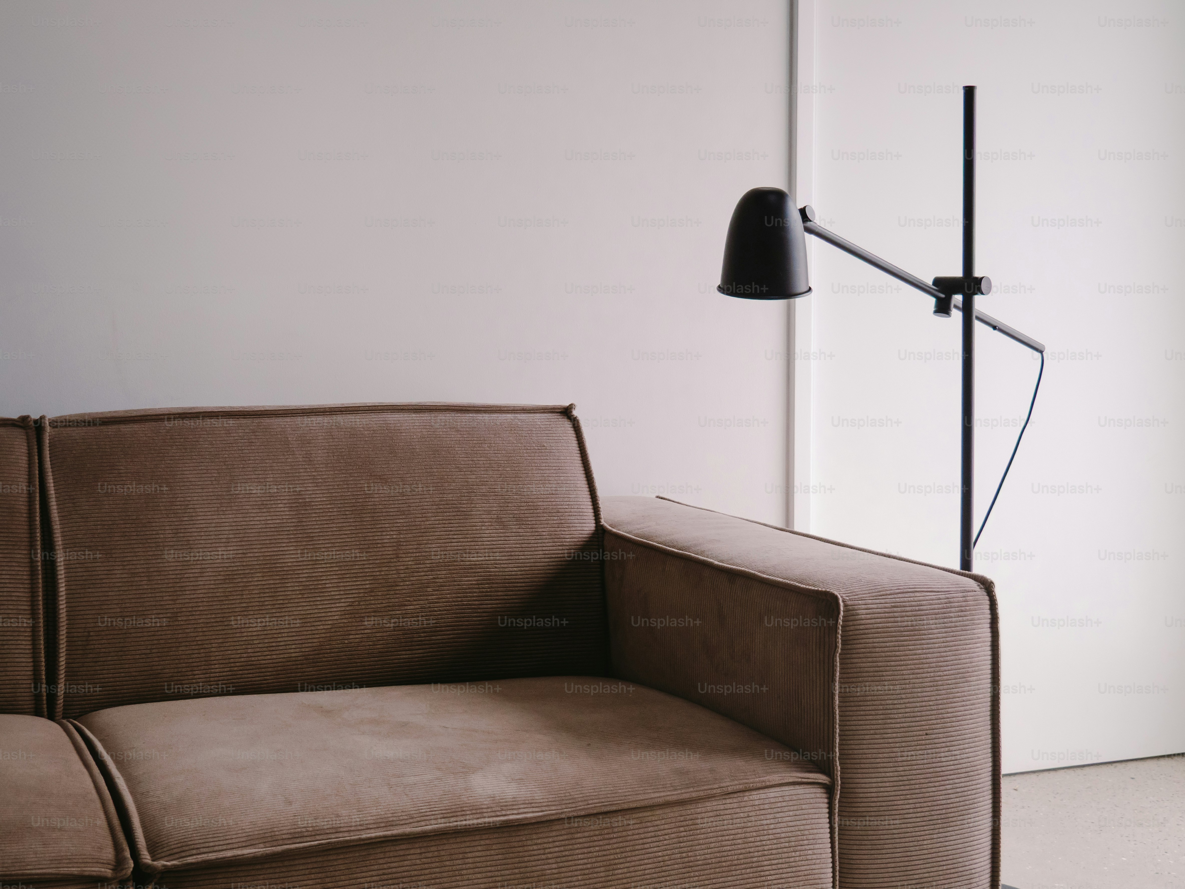 Un sofá marrón con una lámpara negra moderna
