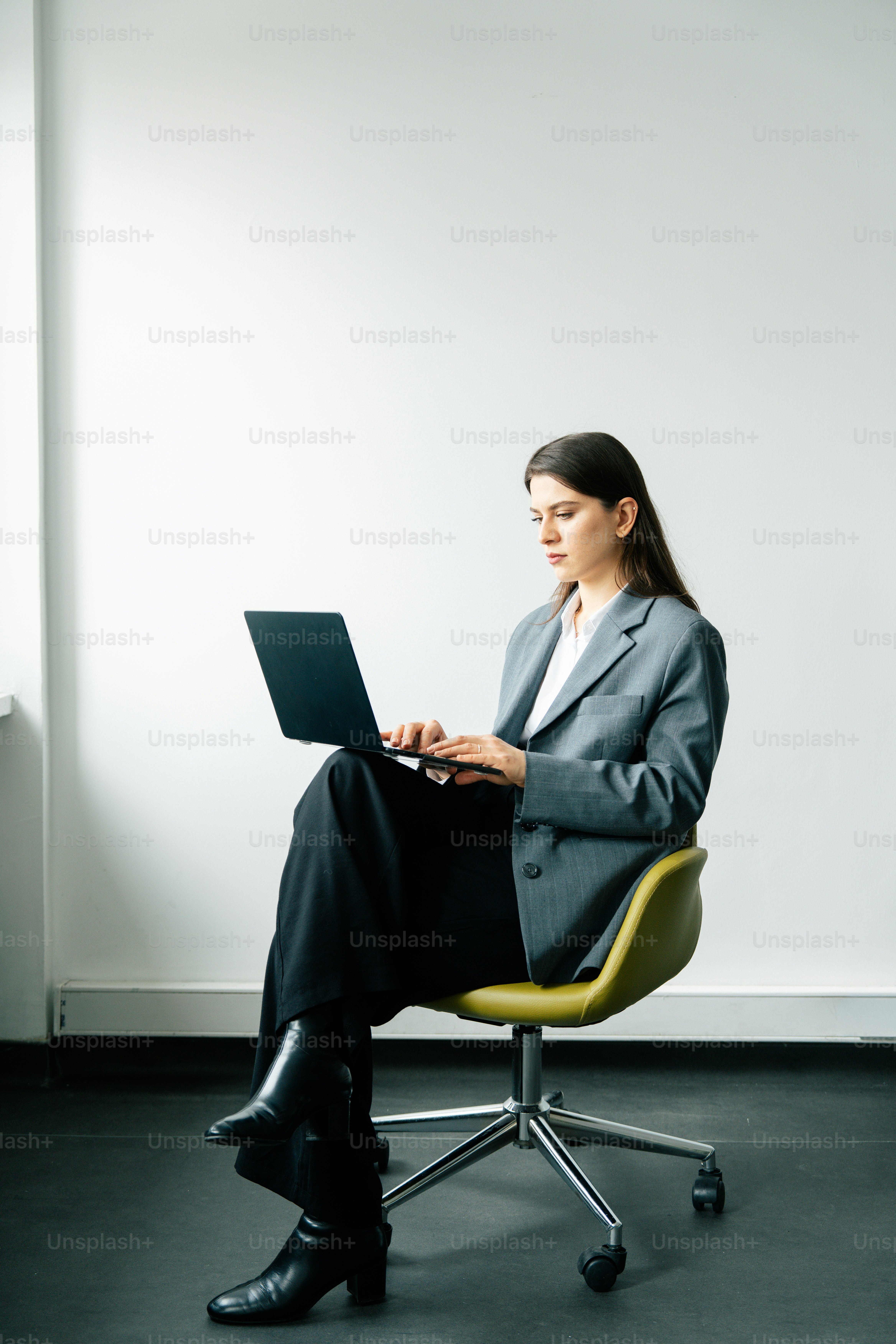 A woman in a suit working on a laptop.