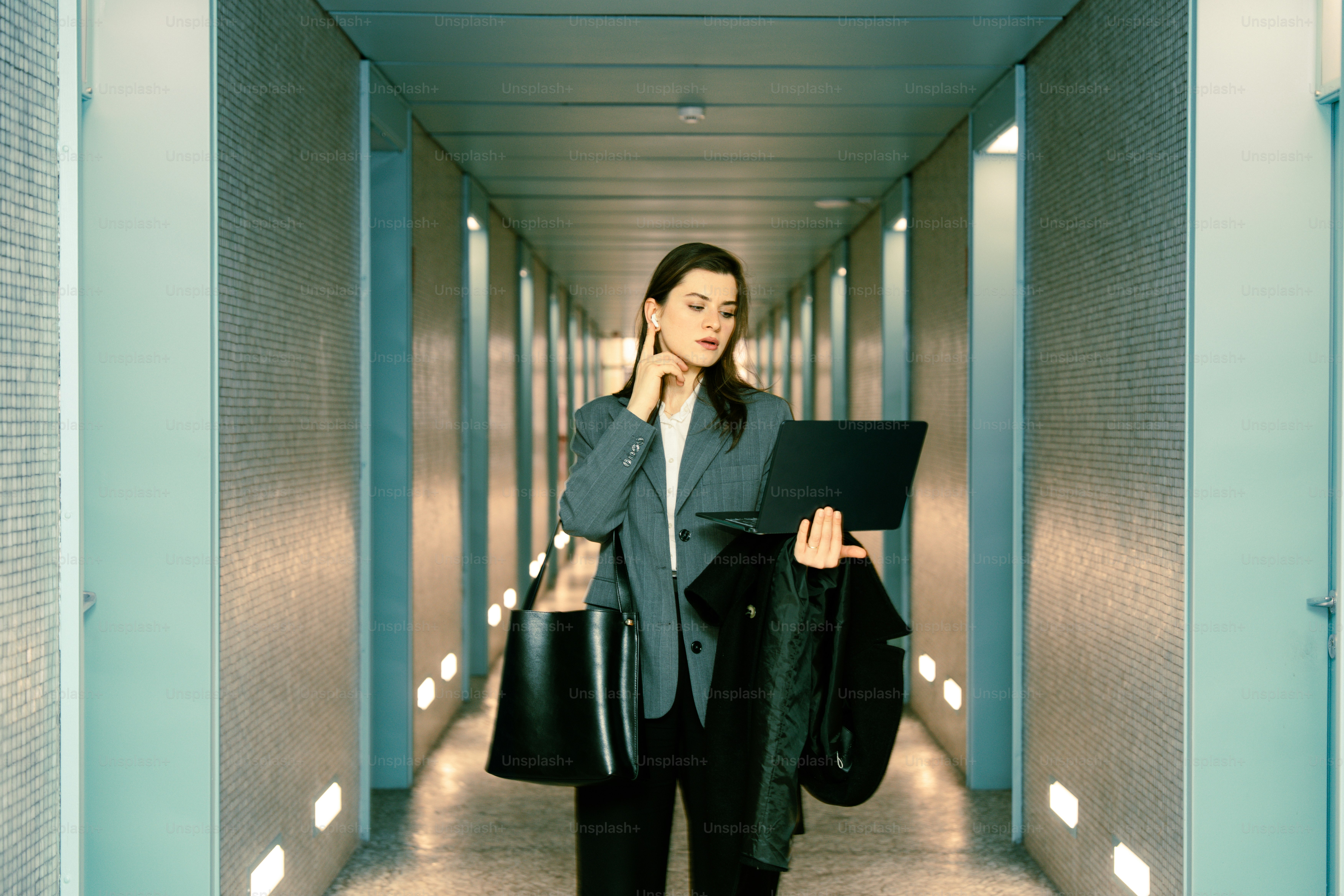 Woman in a suit walking down a hallway.