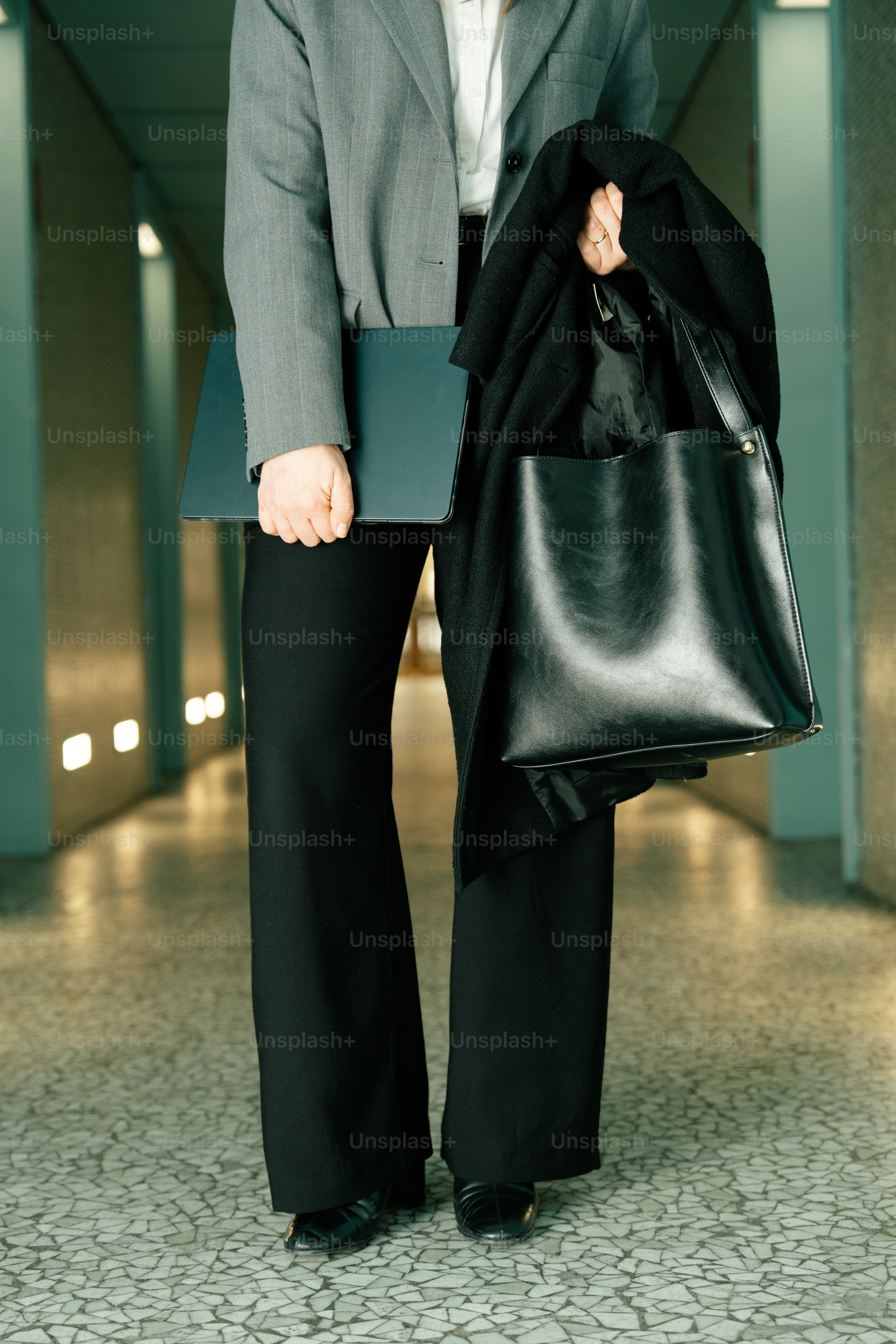 Woman in business attire holding laptop and bag