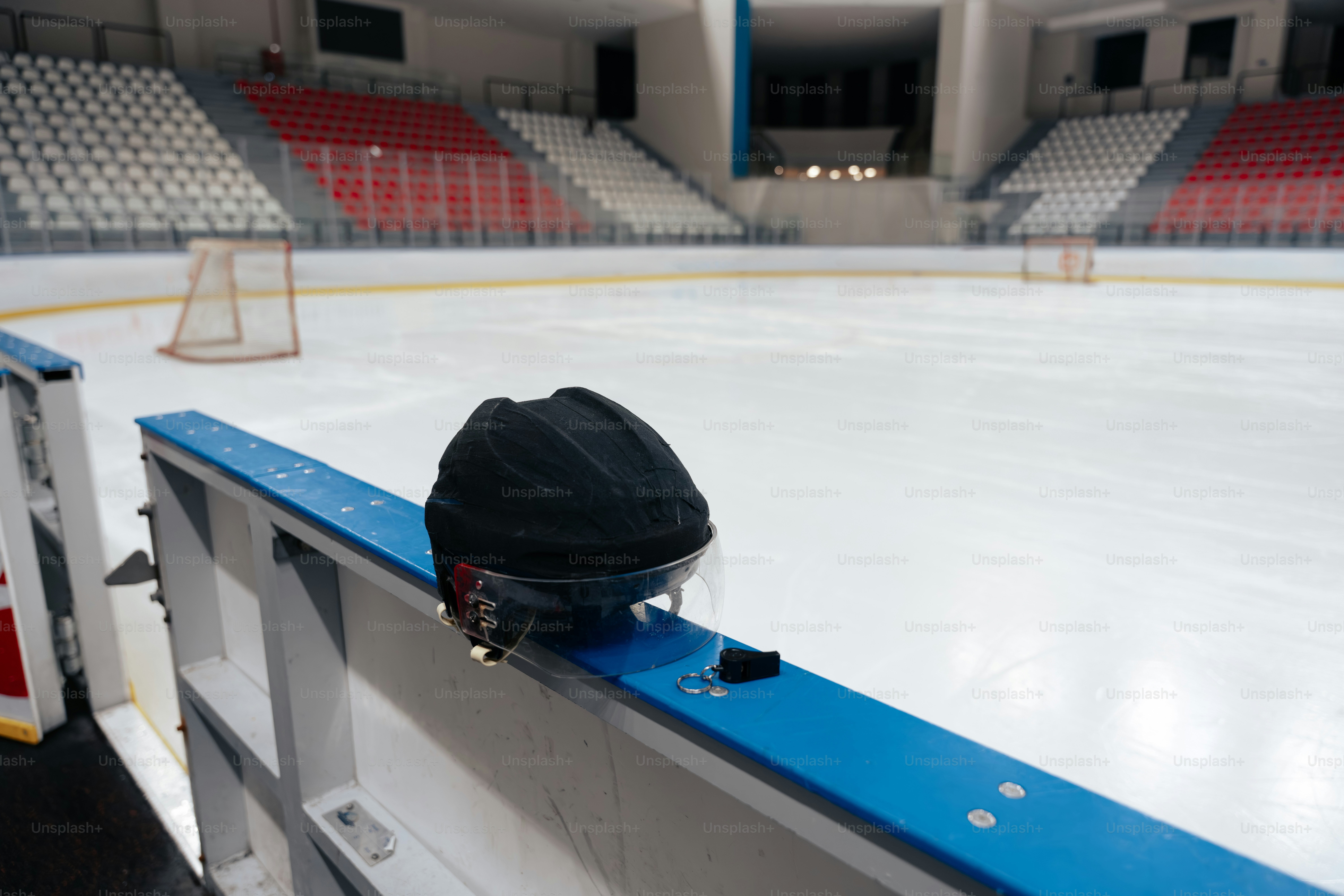 검은색 하키 헬멧이 아레나 대셔 보드 위에 놓여 있다
