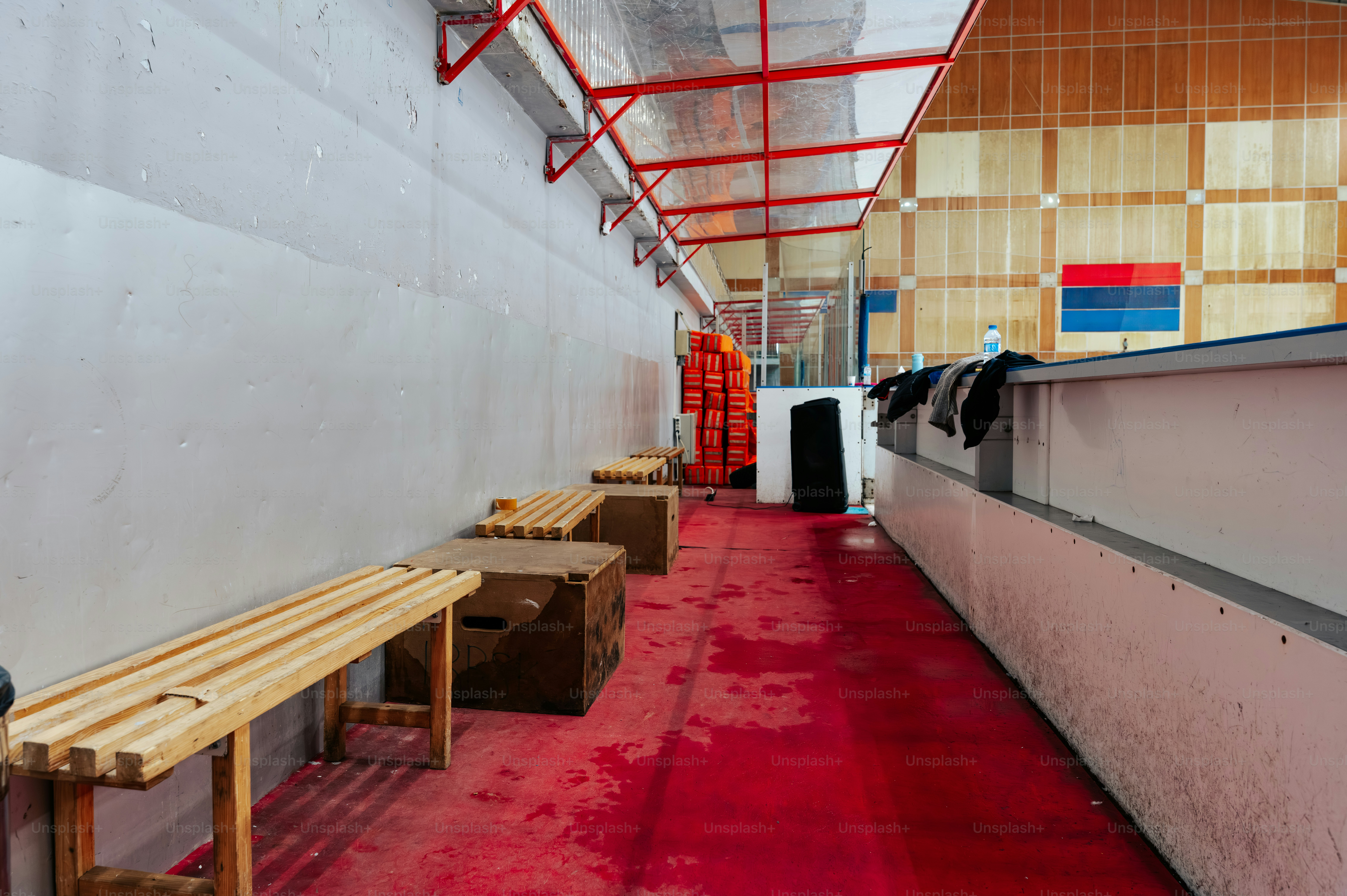 나무 벤치와 빨간 바닥이 있는 빈 라커룸