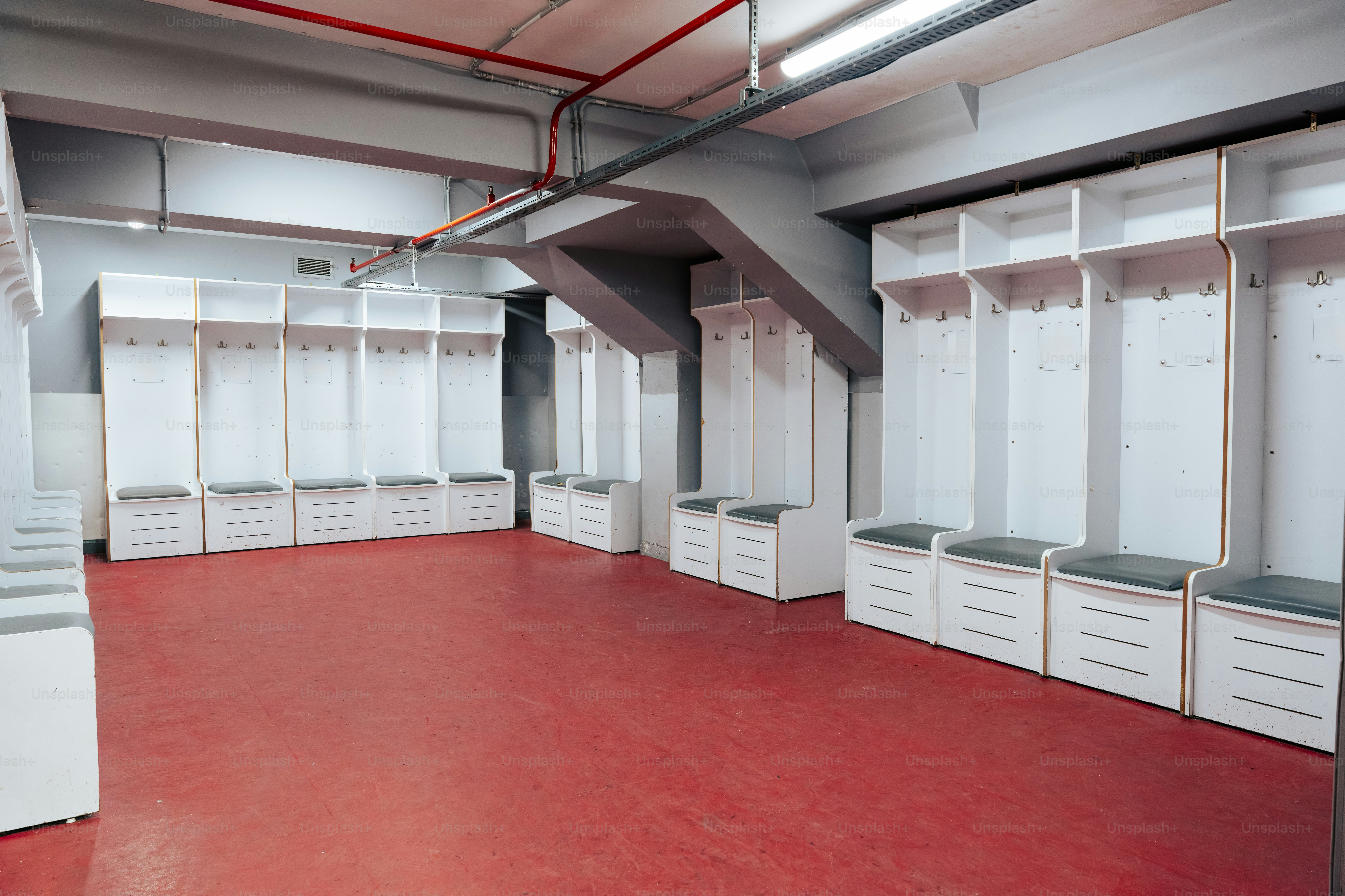 Empty locker room with white lockers and red floor