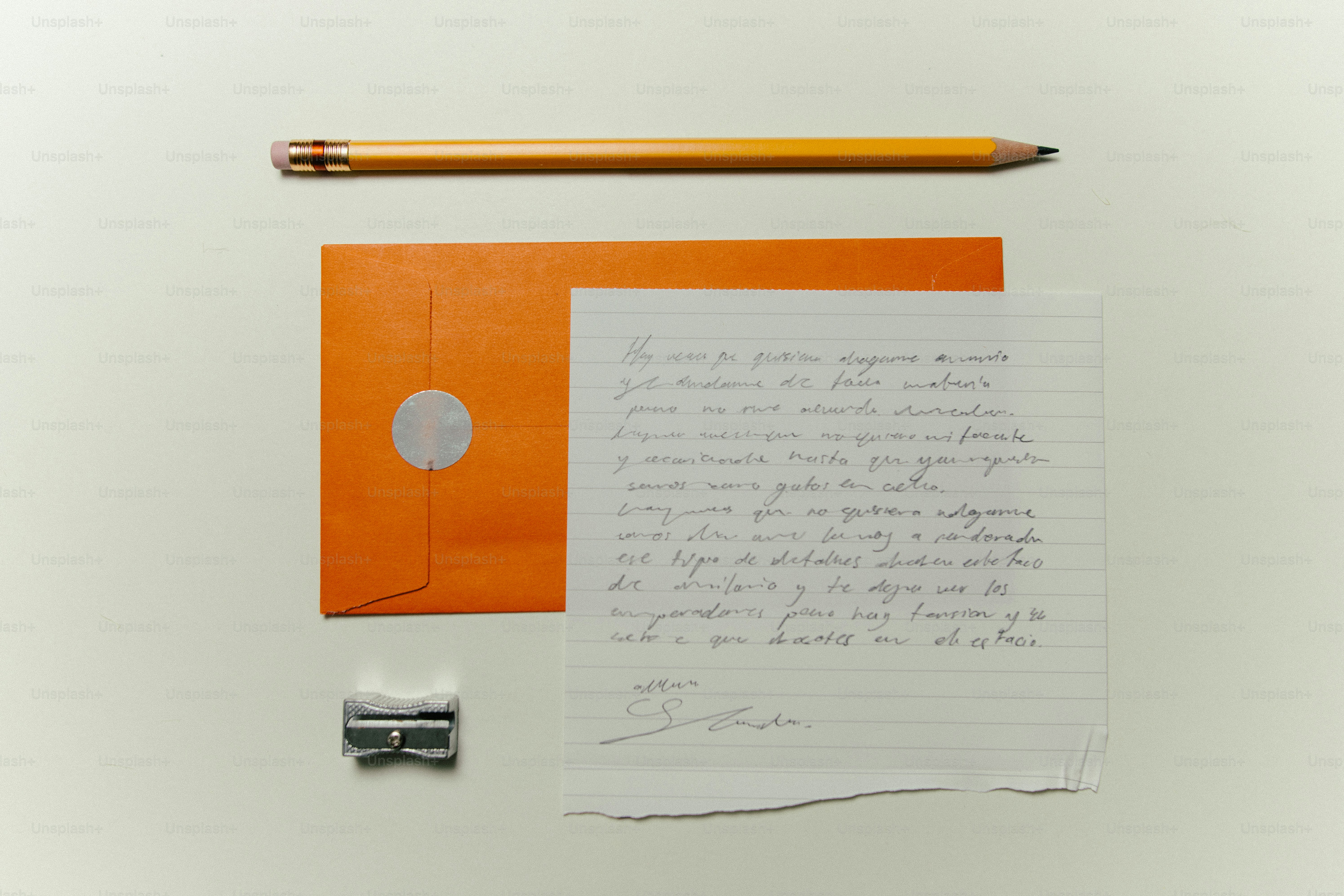 Pencil, envelope, letter, and sharpener on white surface