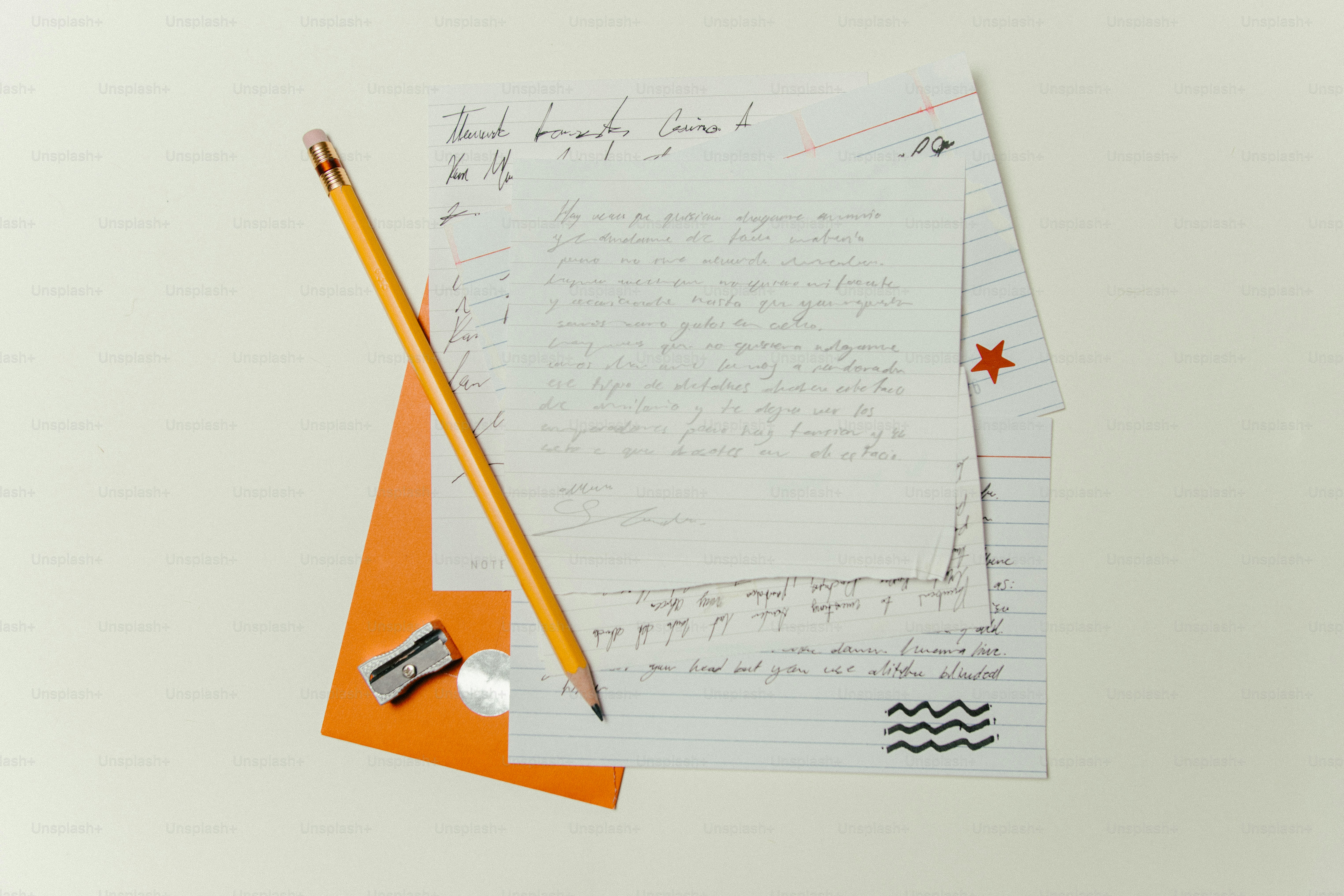 A pencil, sharpener, and handwritten letters on a desk.