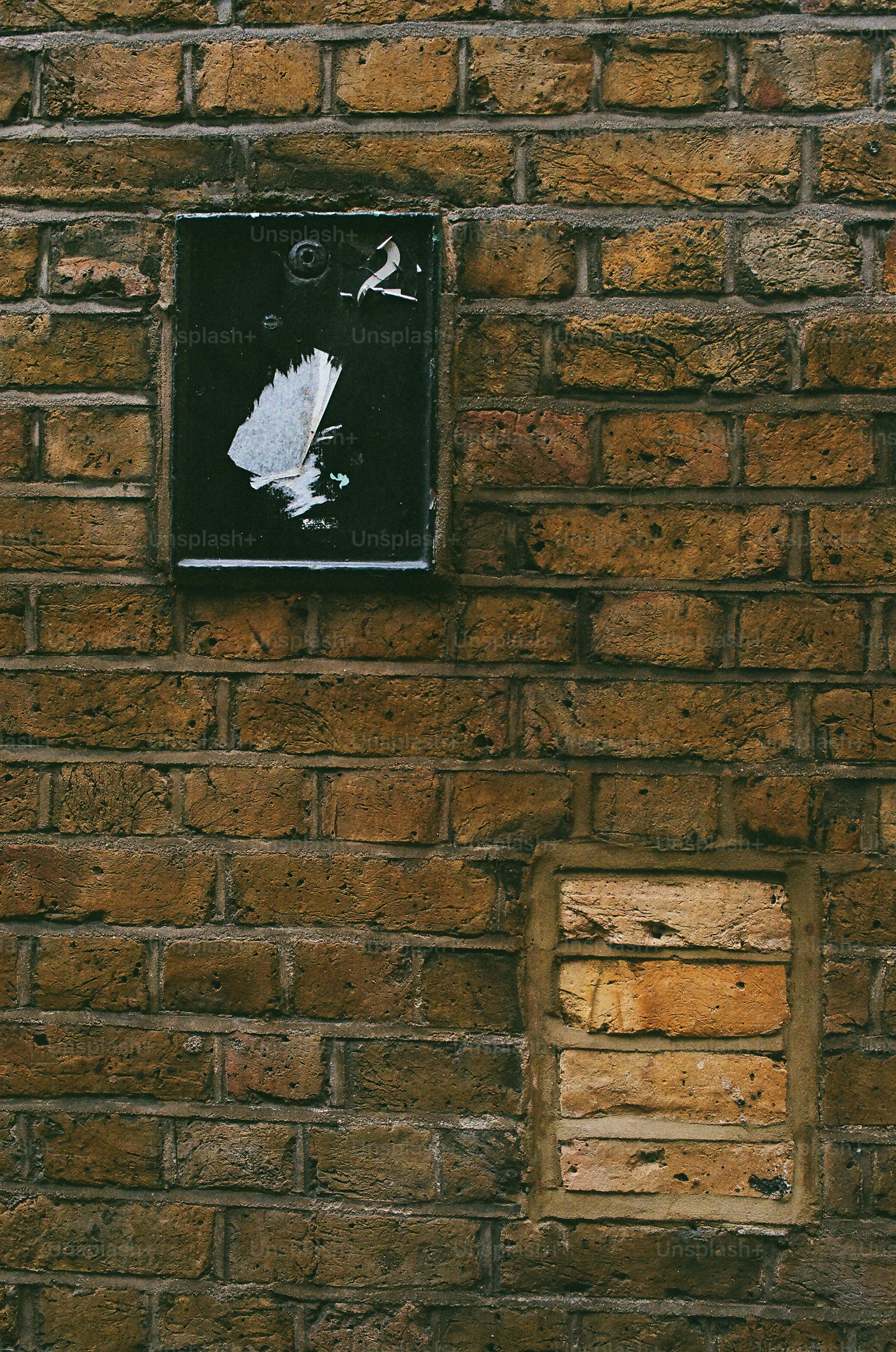Uma parede de tijolos desgastada com uma placa escura.