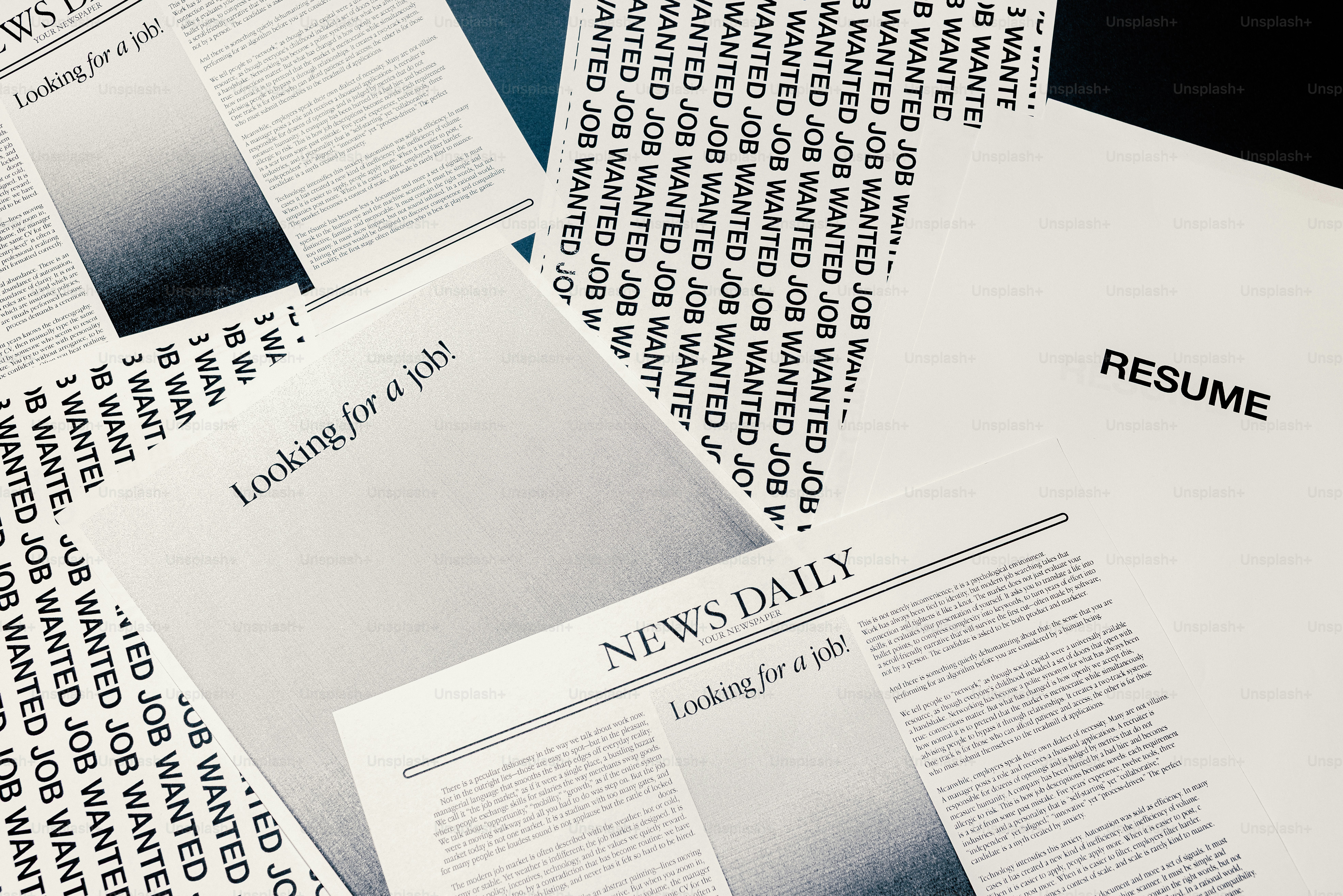Resumes and newspapers scattered on a surface.