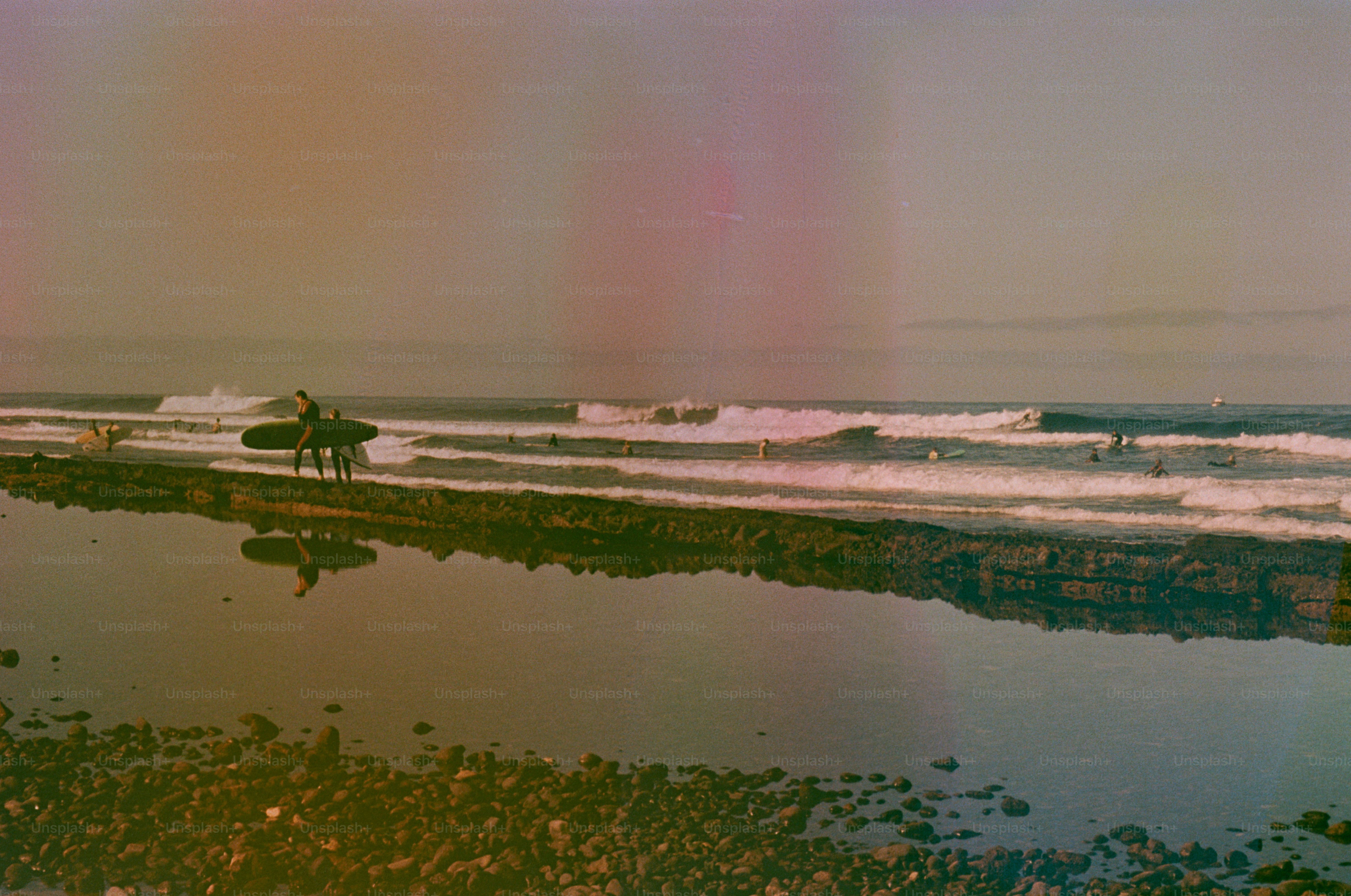 Surfers with surfboards walk along the shore