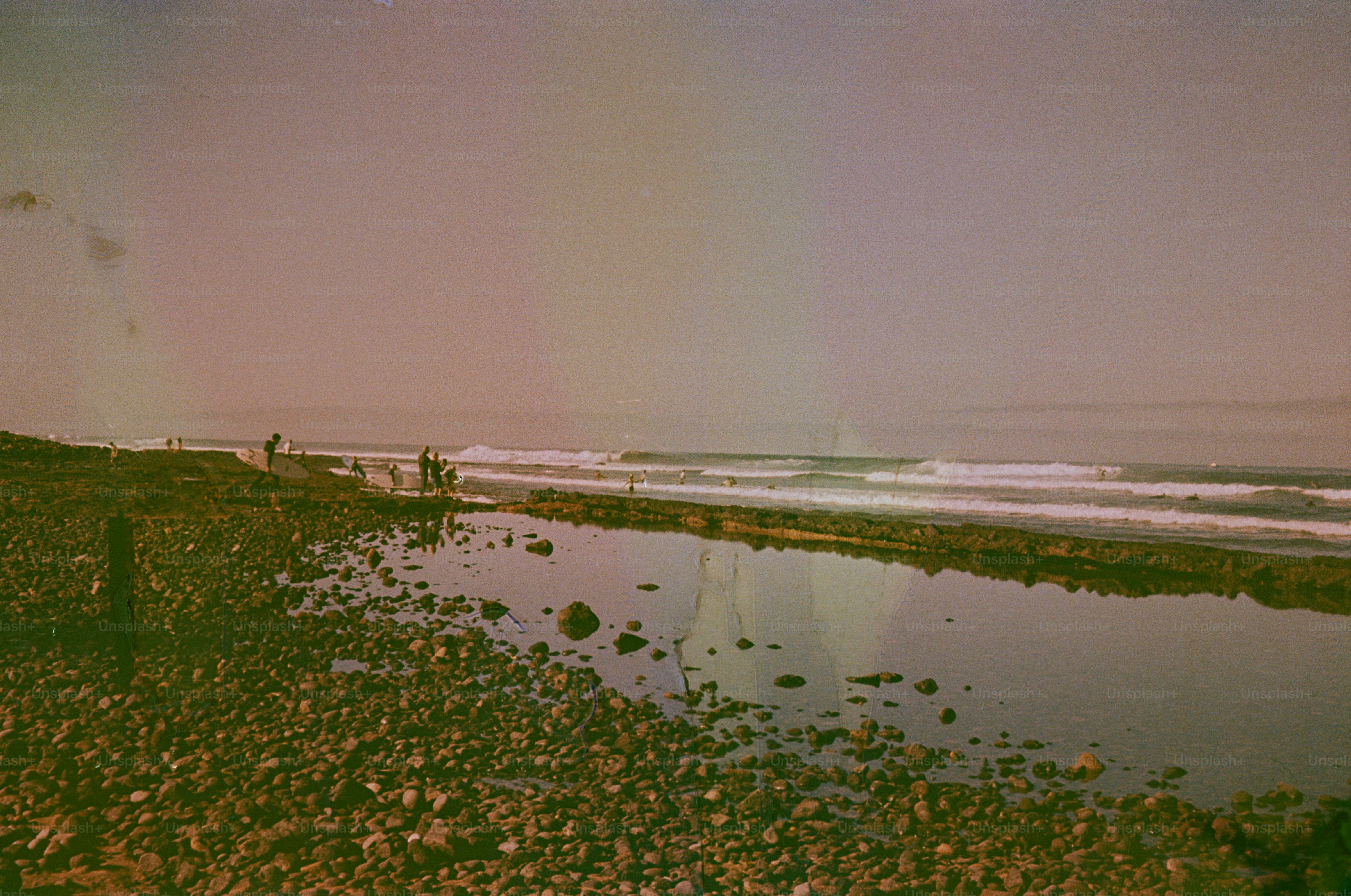 Rocky beach with gentle waves and distant people.