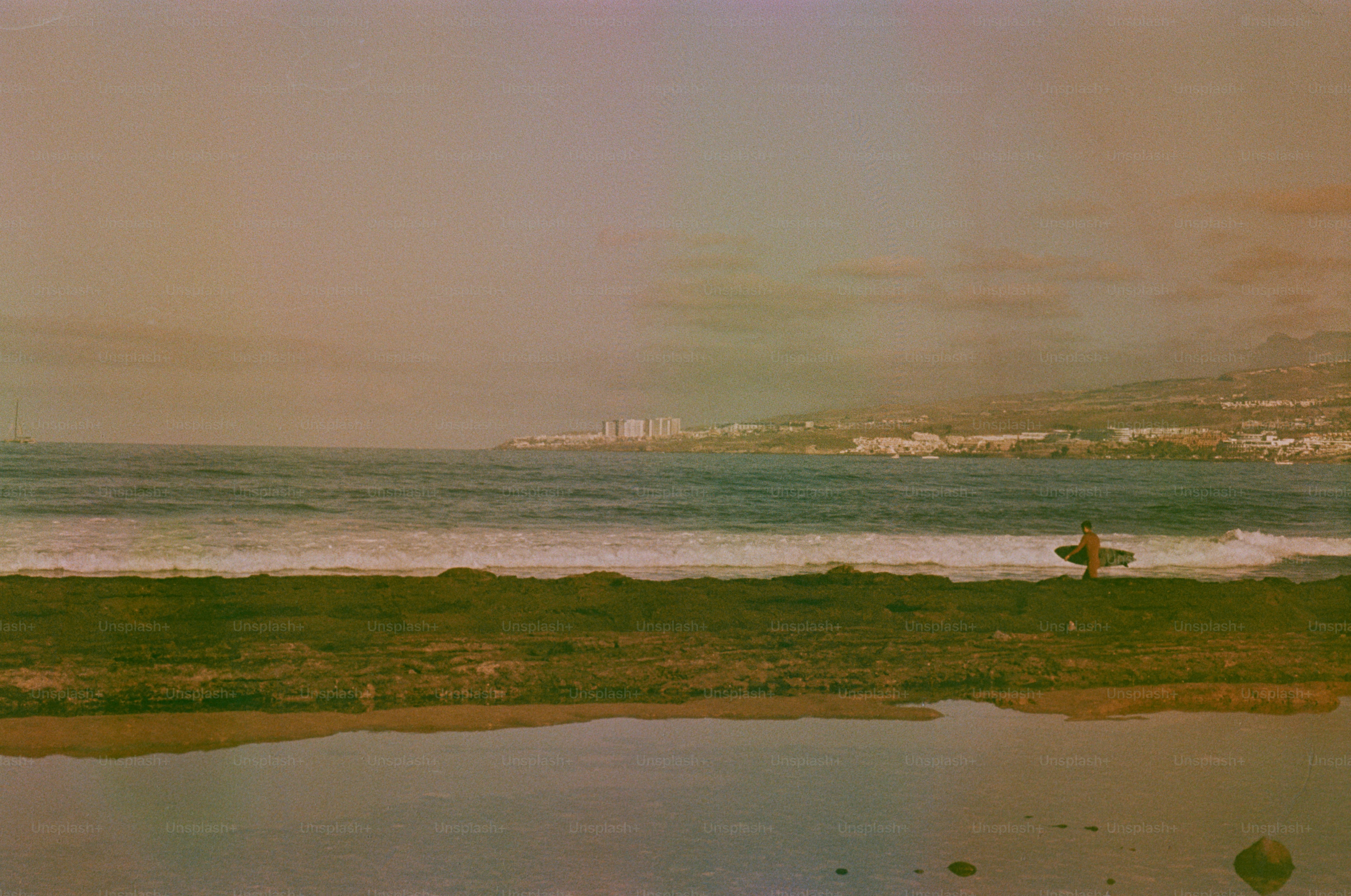 Surfer with surfboard on beach near ocean