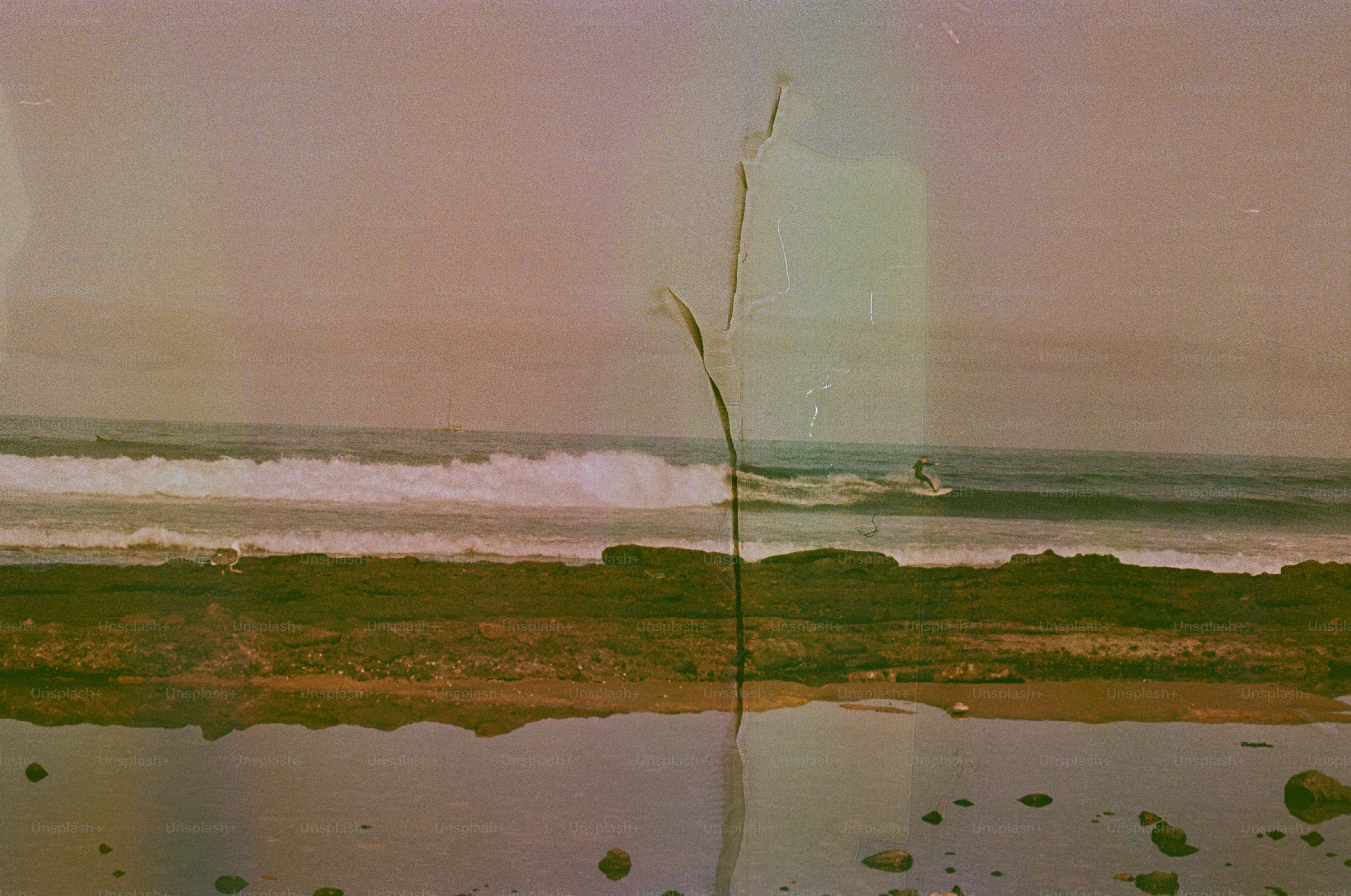 Waves crash on a rocky shore under a hazy sky.