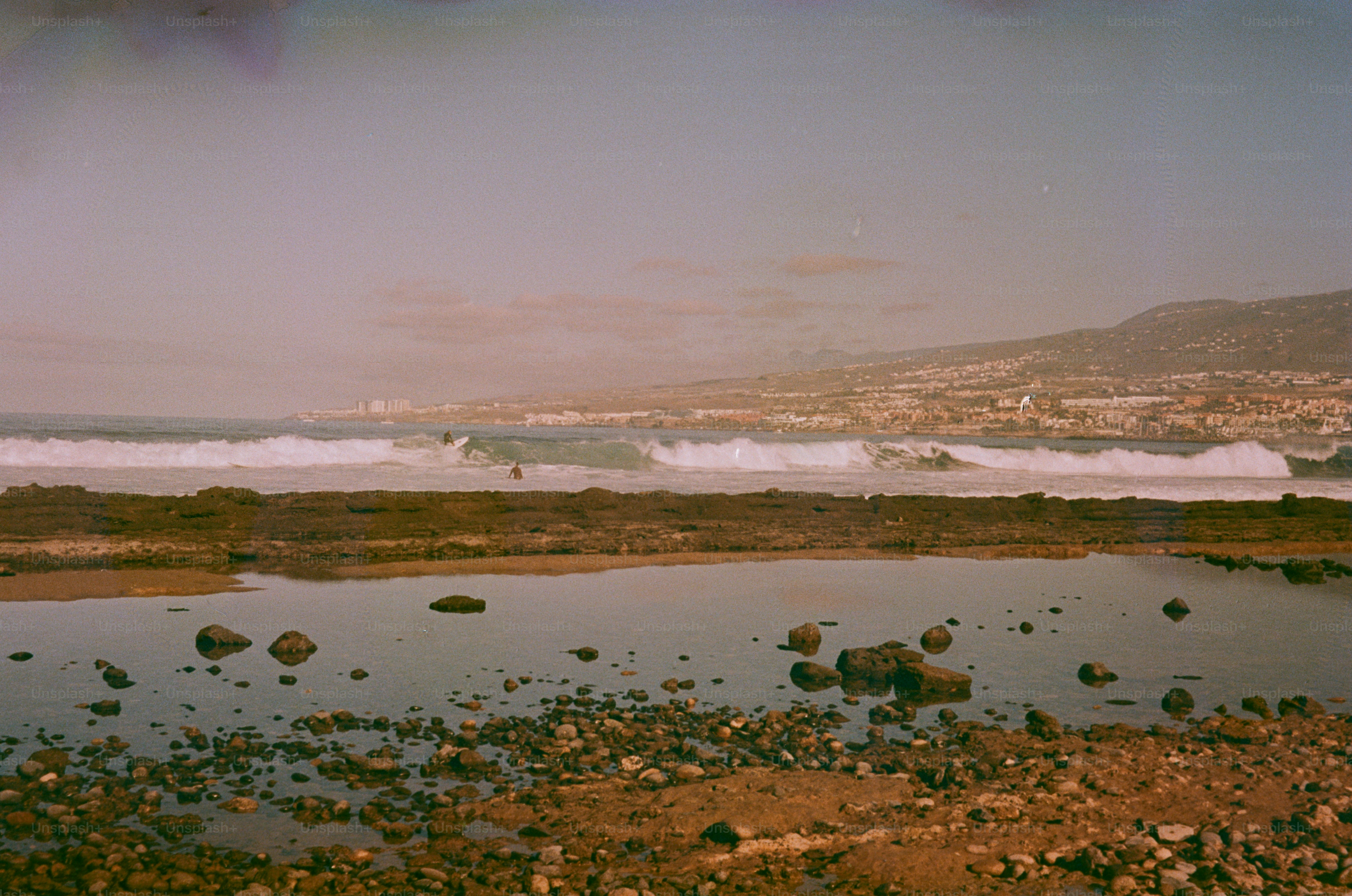 Surfers ride waves near a coastal town.