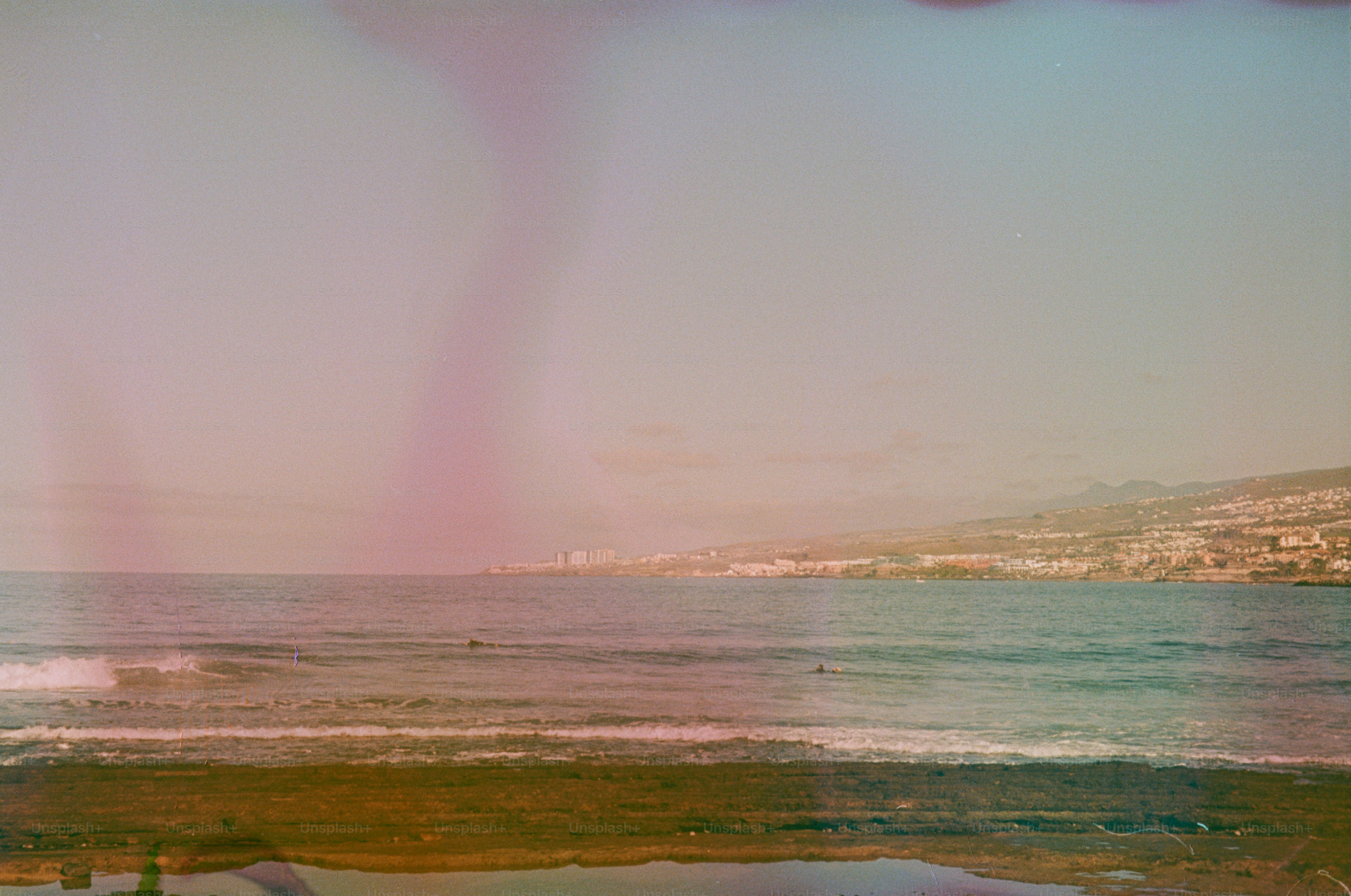 Ocean waves near a coastal town under a hazy sky