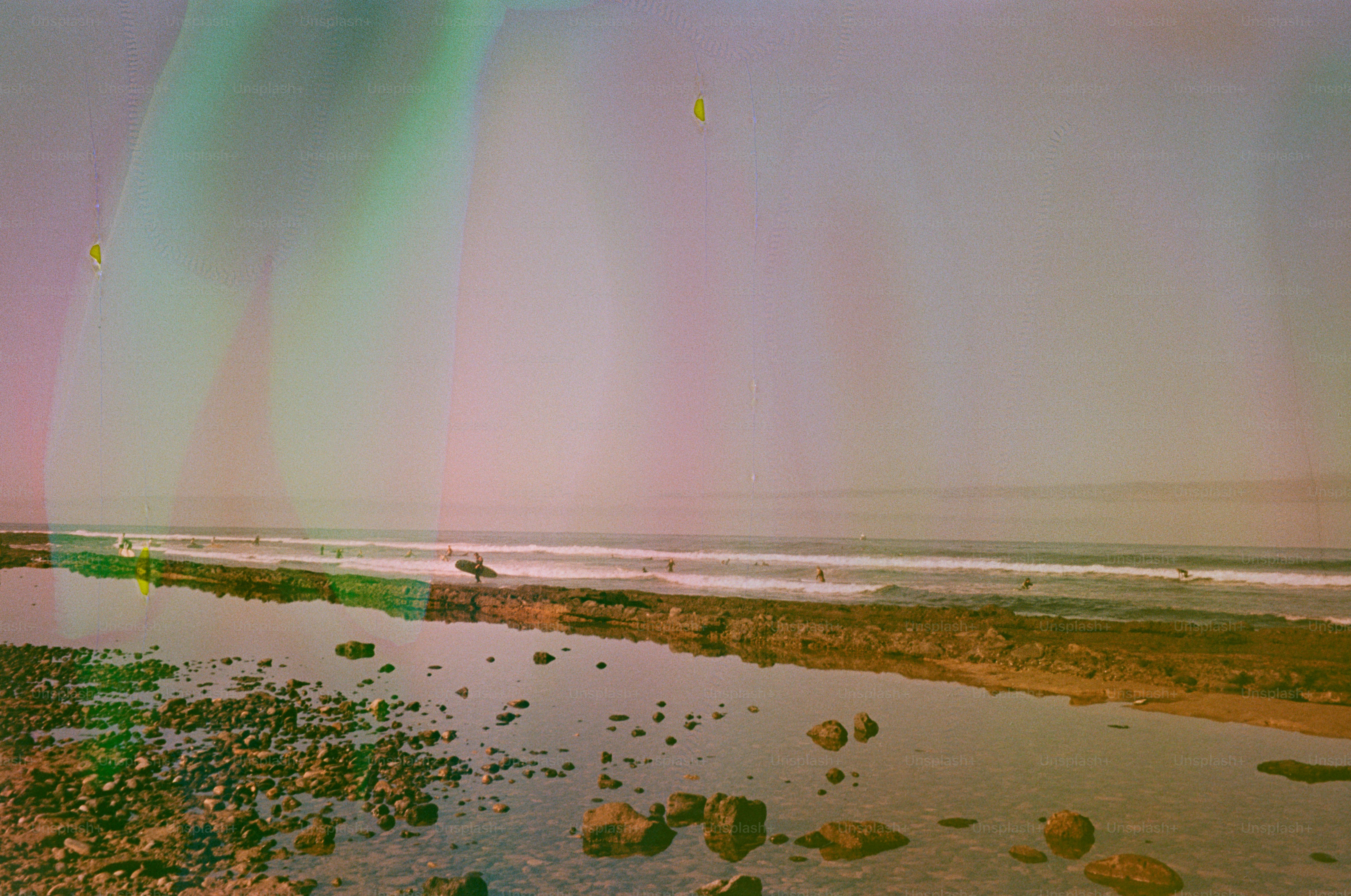 Surfer with surfboard walks along rocky beach towards ocean