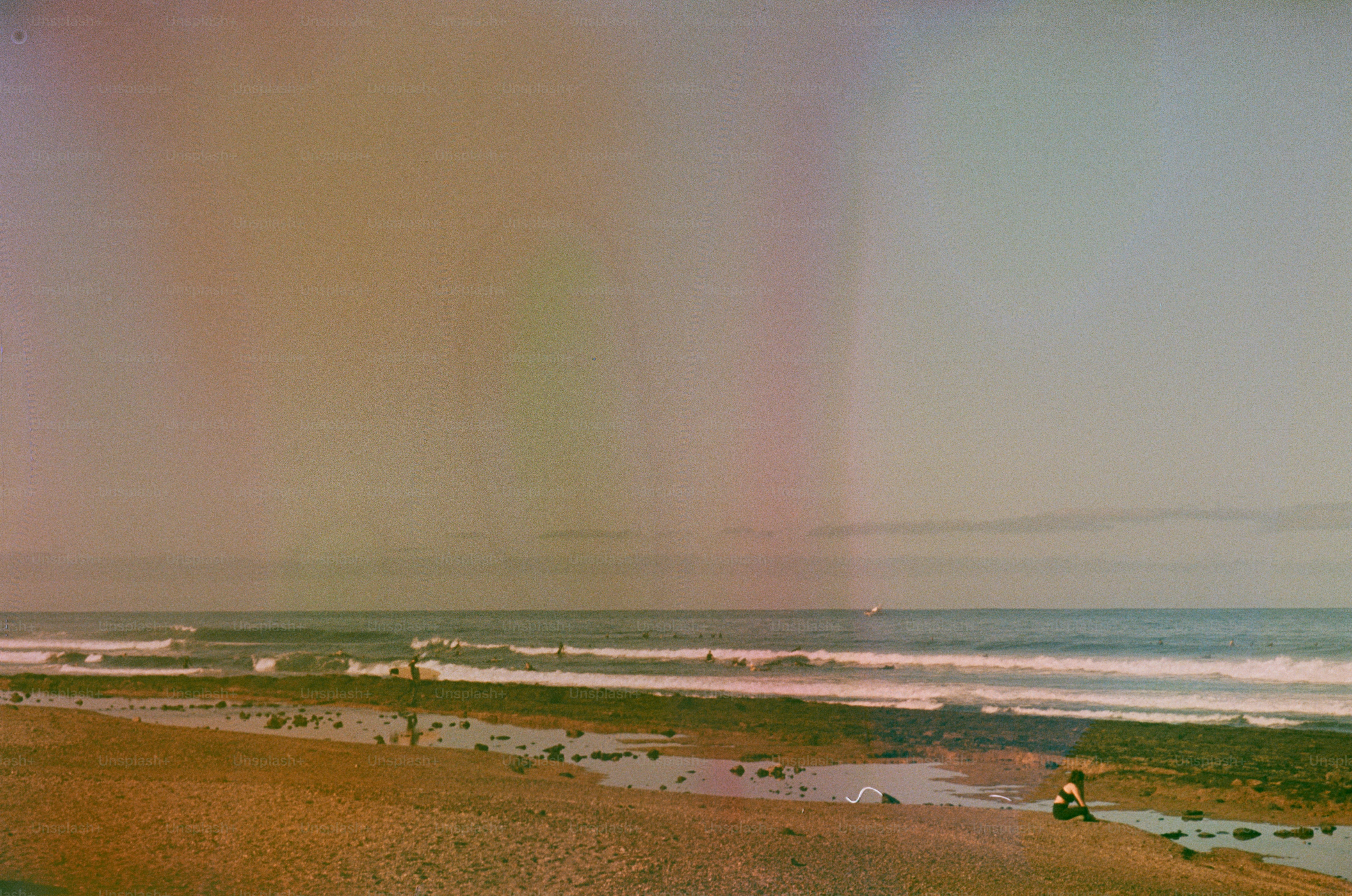 People on a beach with waves and a calm sea.