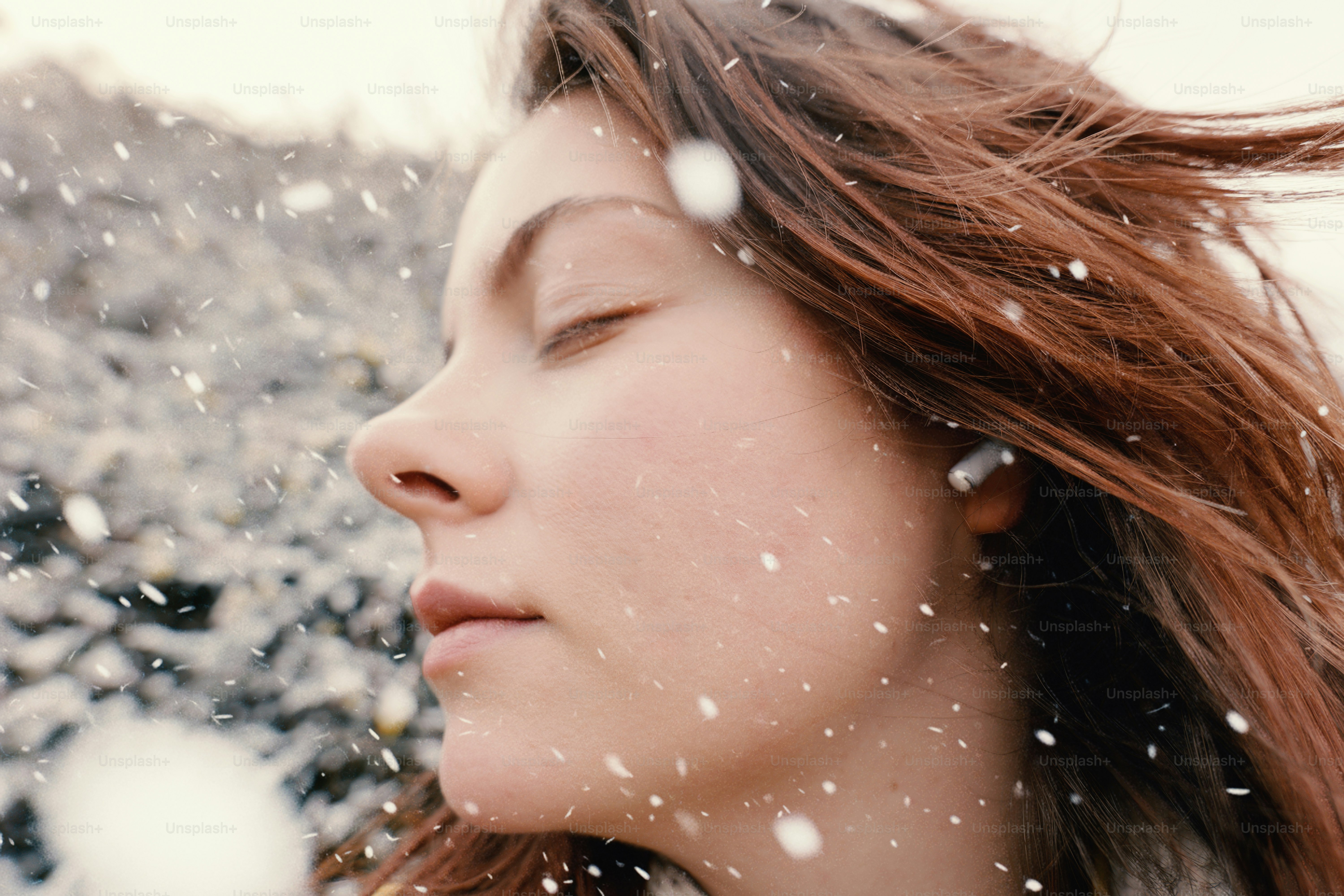 Young woman with eyes closed in falling snow