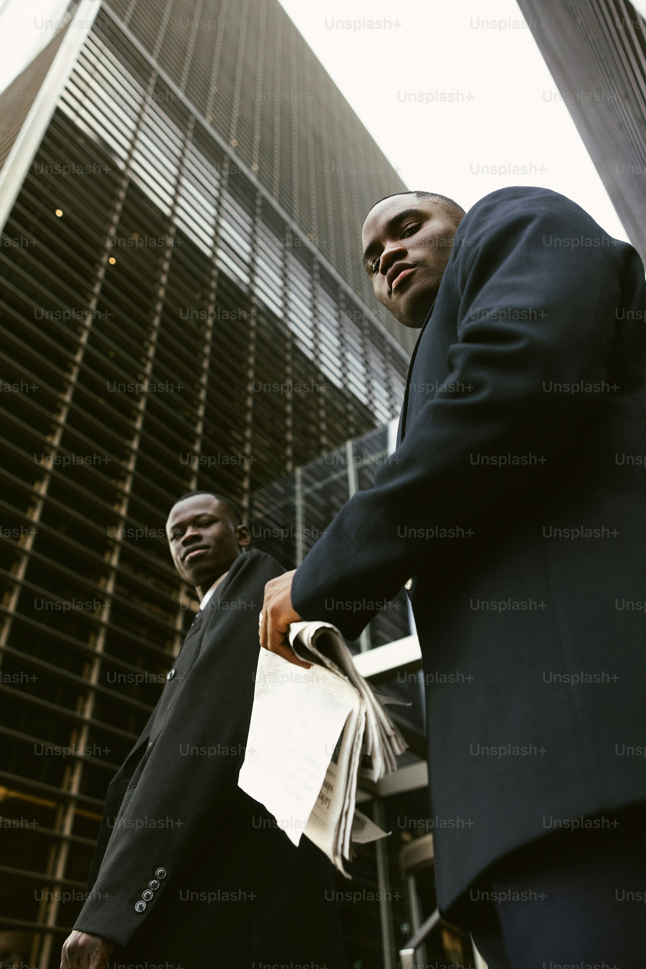 Two men in suits walk past a modern building.
