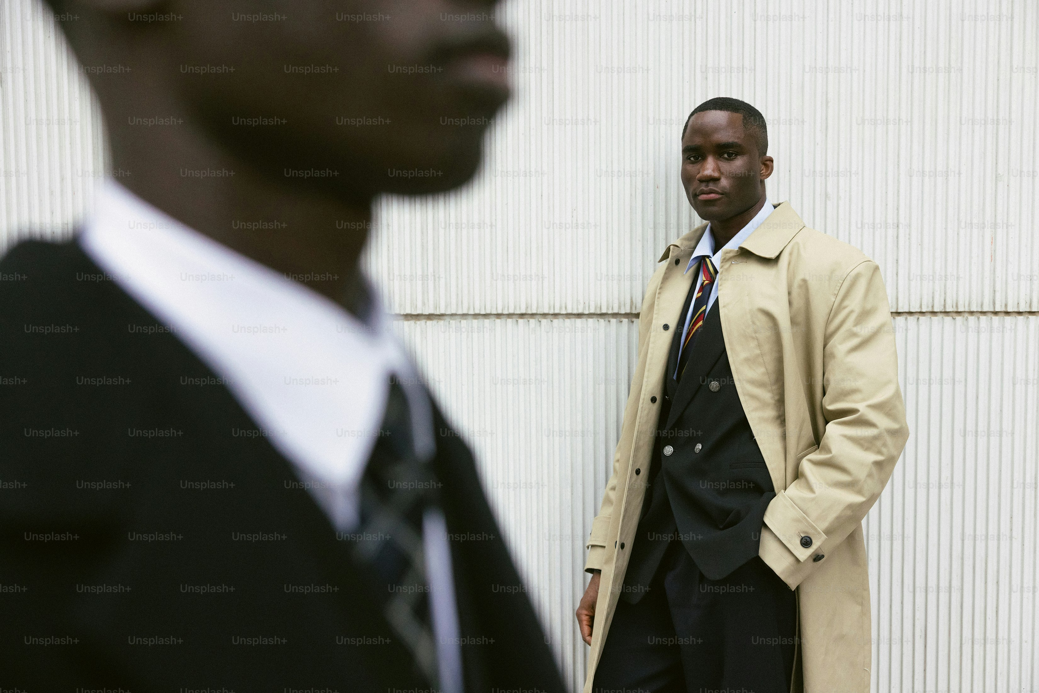 Two men in suits standing against a wall