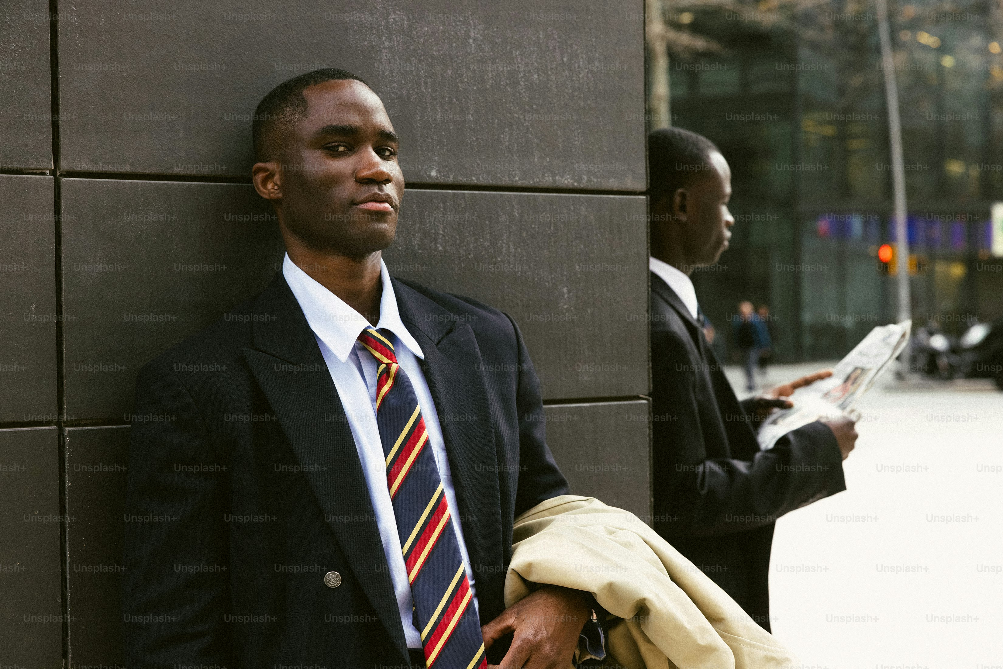 Man in suit leaning against wall with reflection