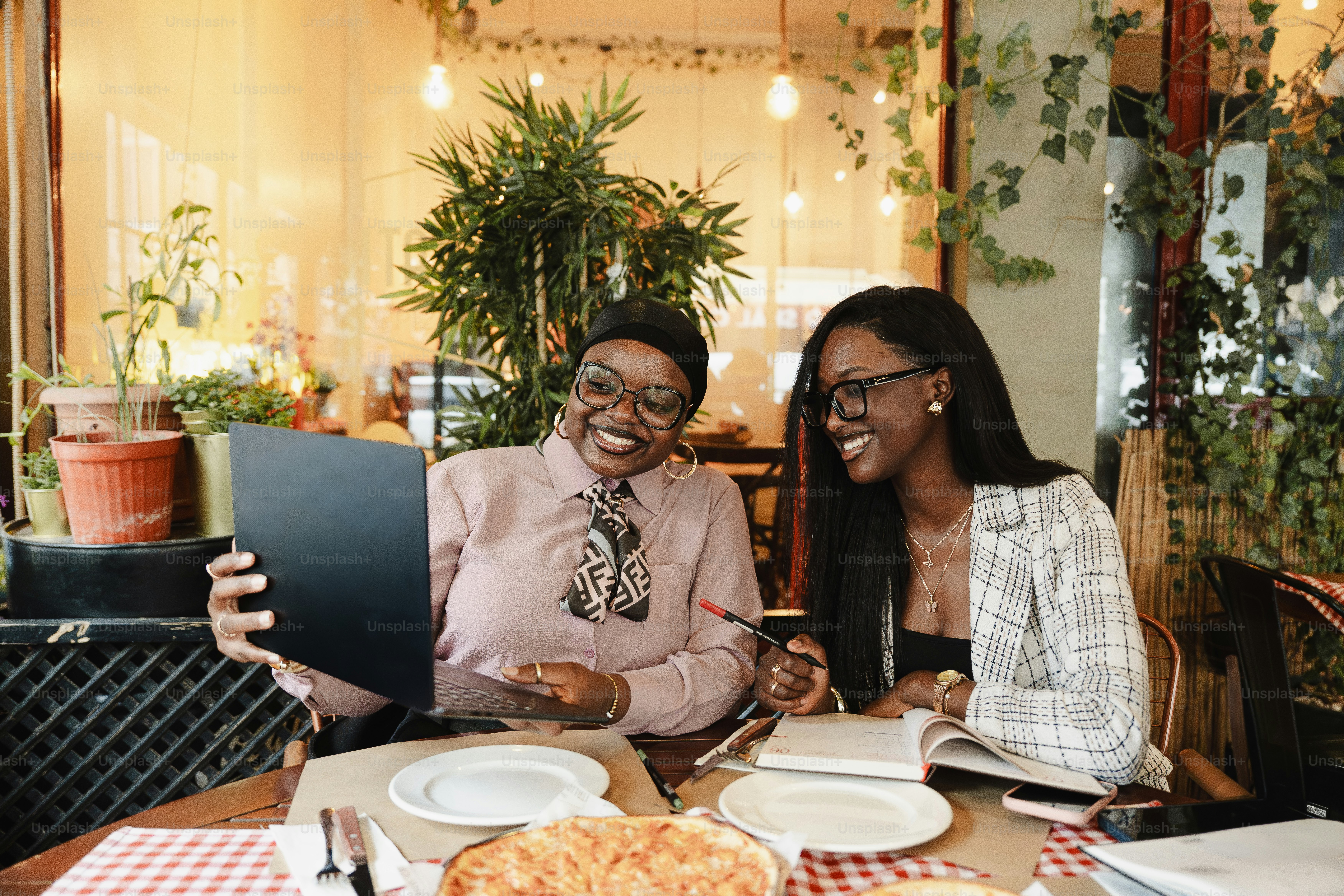 Duas mulheres olhando para um tablet na mesa de um restaurante.
