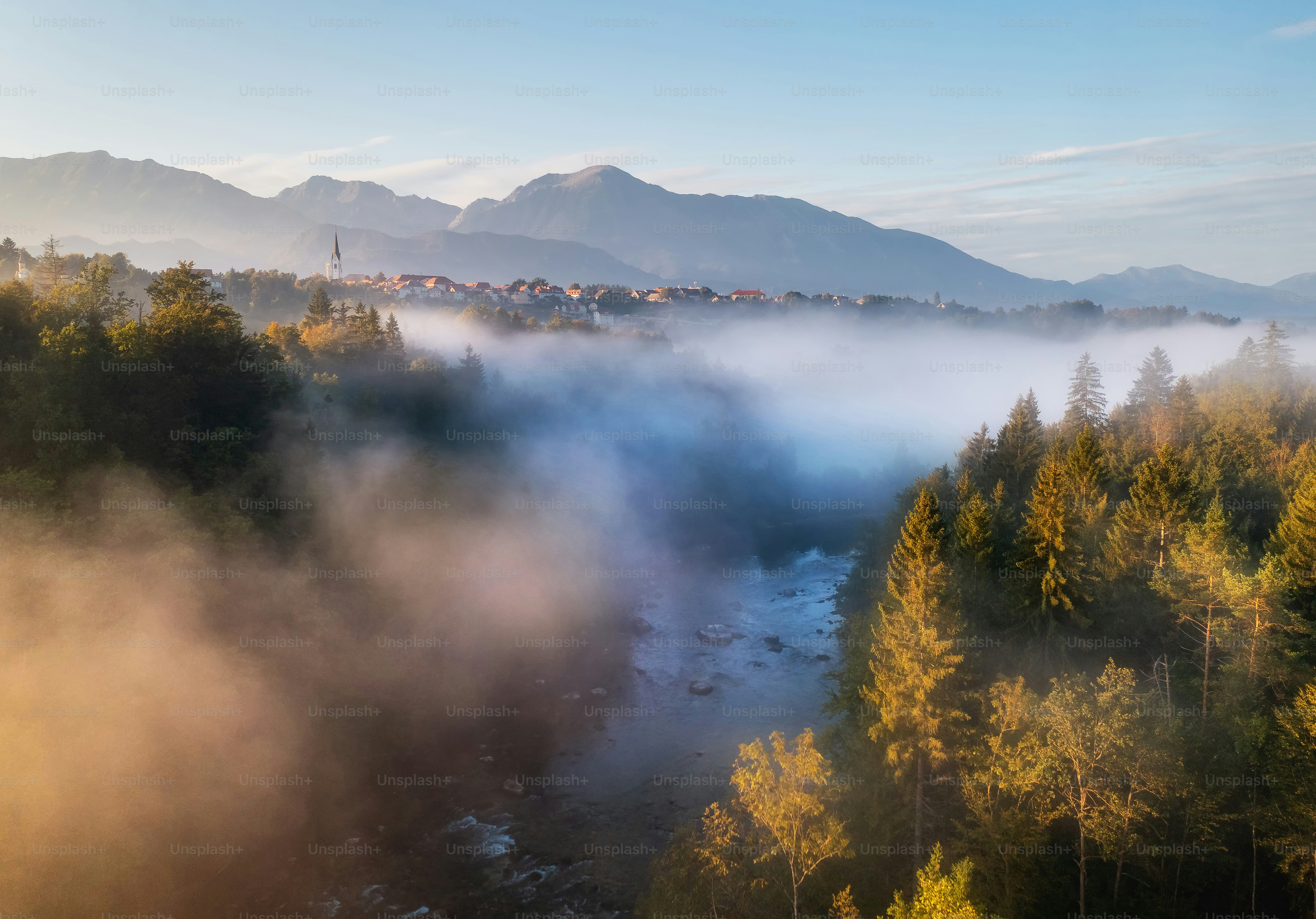 Der Nebelfluss fließt durch einen Wald in Richtung Berge.