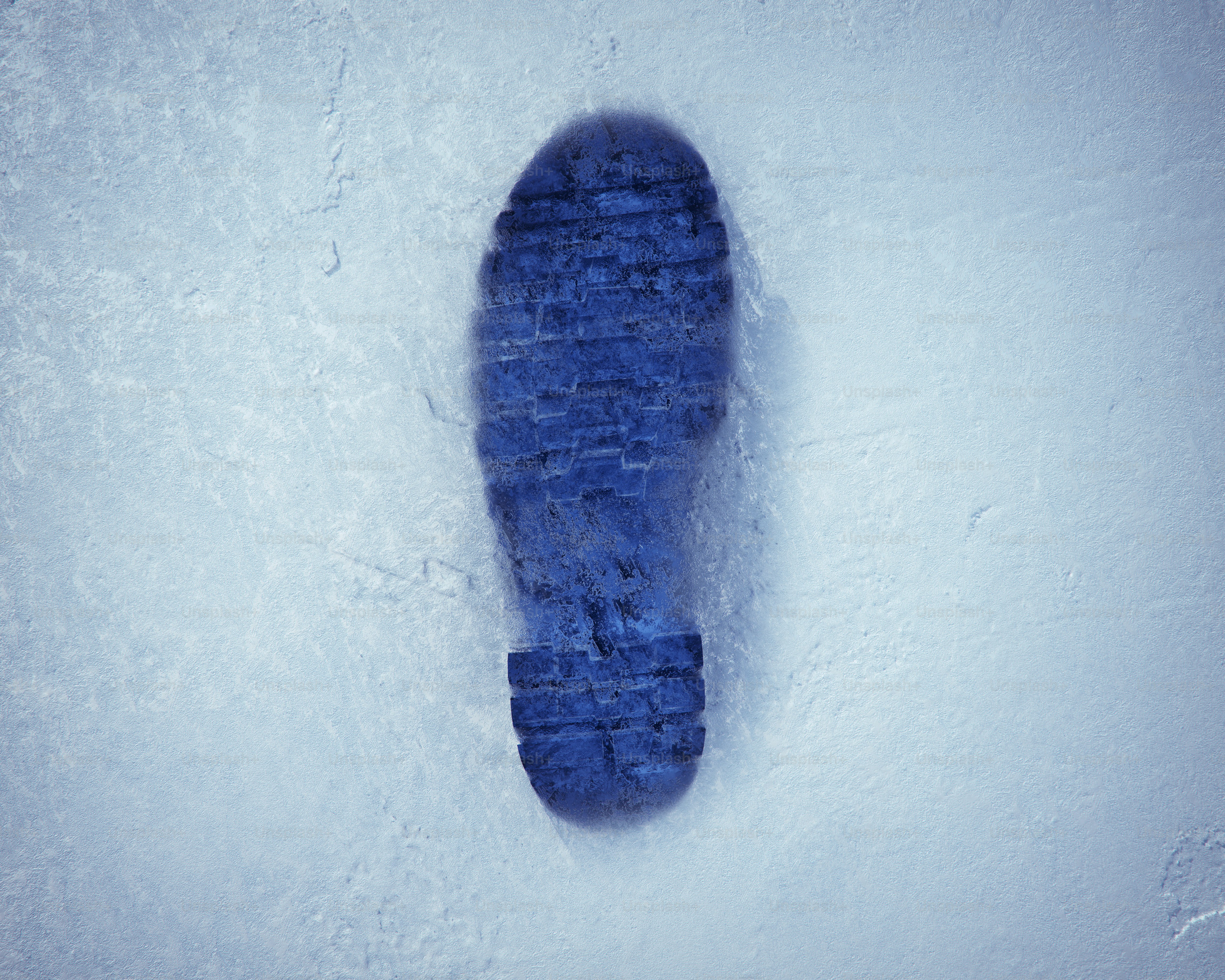 A blue footprint pressed into white snow