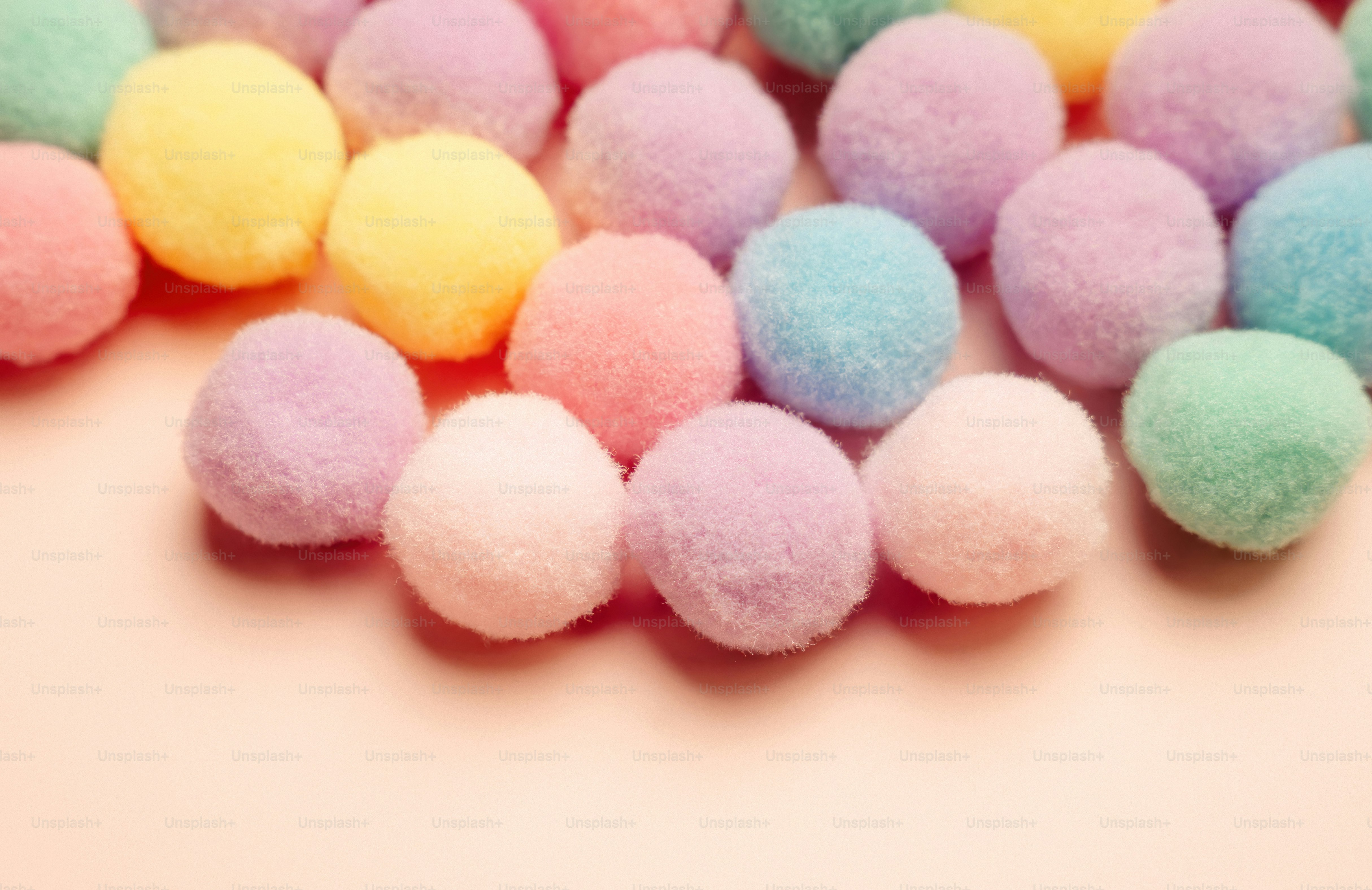 A collection of pastel colored pom-poms on a pink background