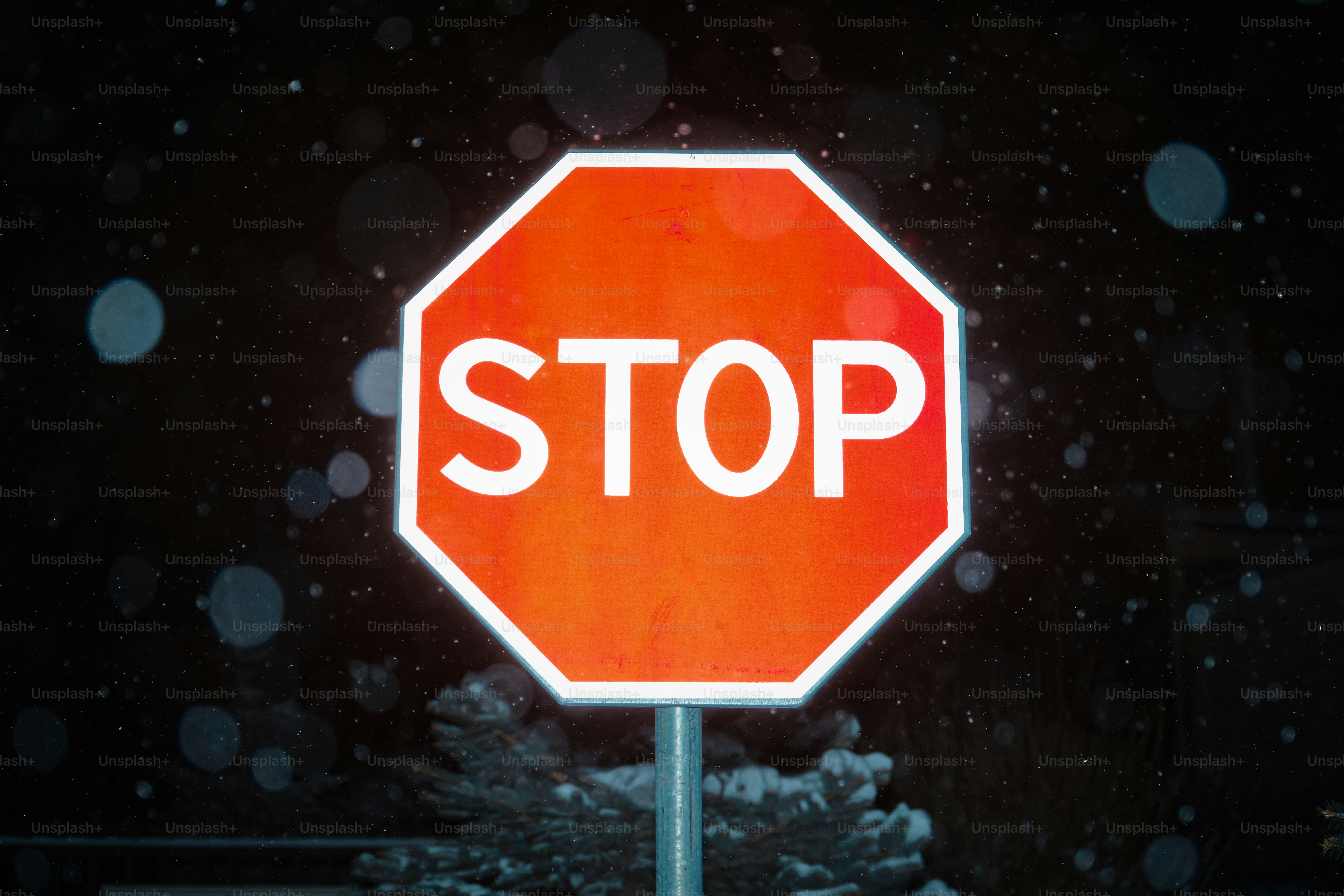 Stop sign illuminated at night with falling snow