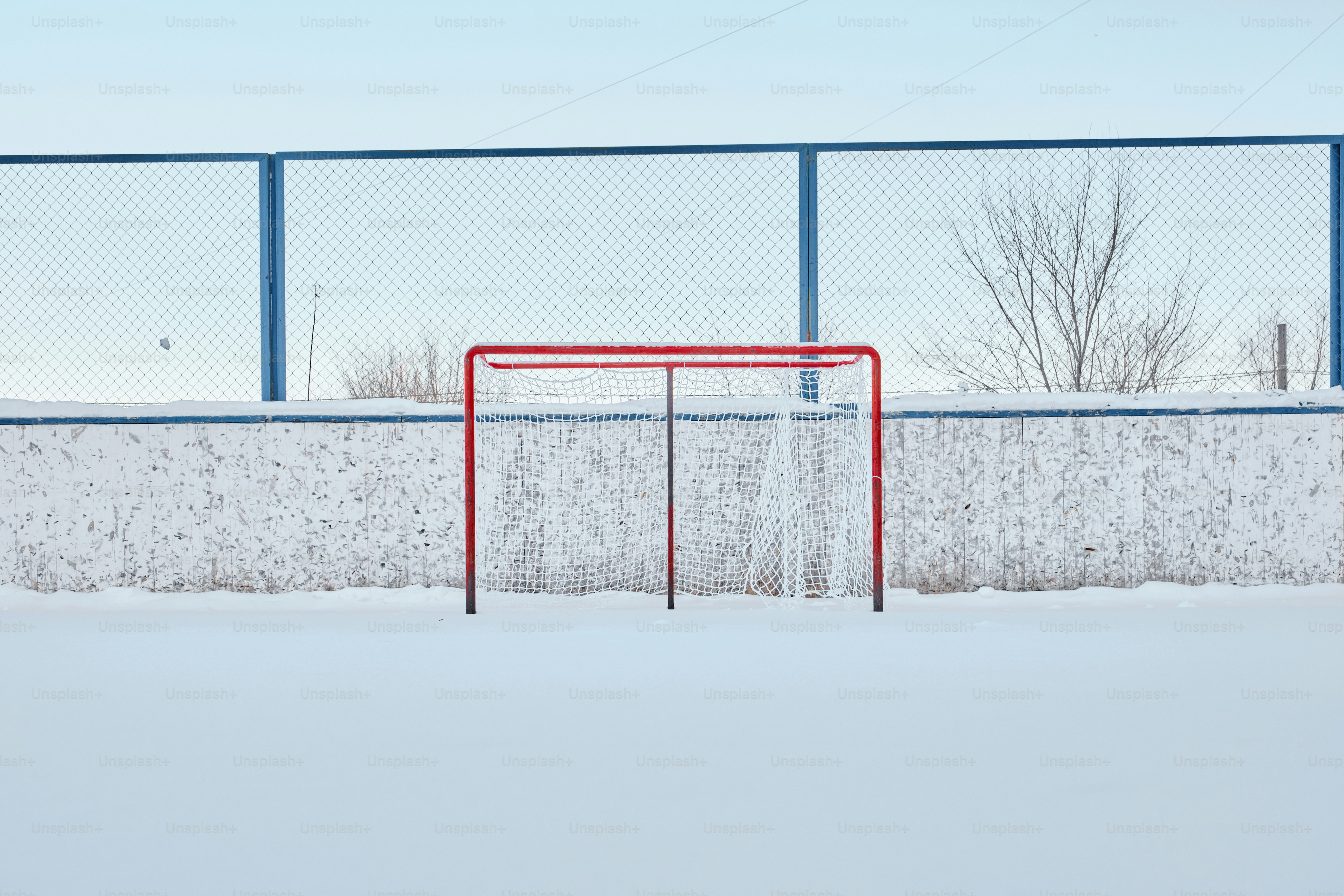 Gol de hóquei vermelho em uma pista externa coberta de neve.