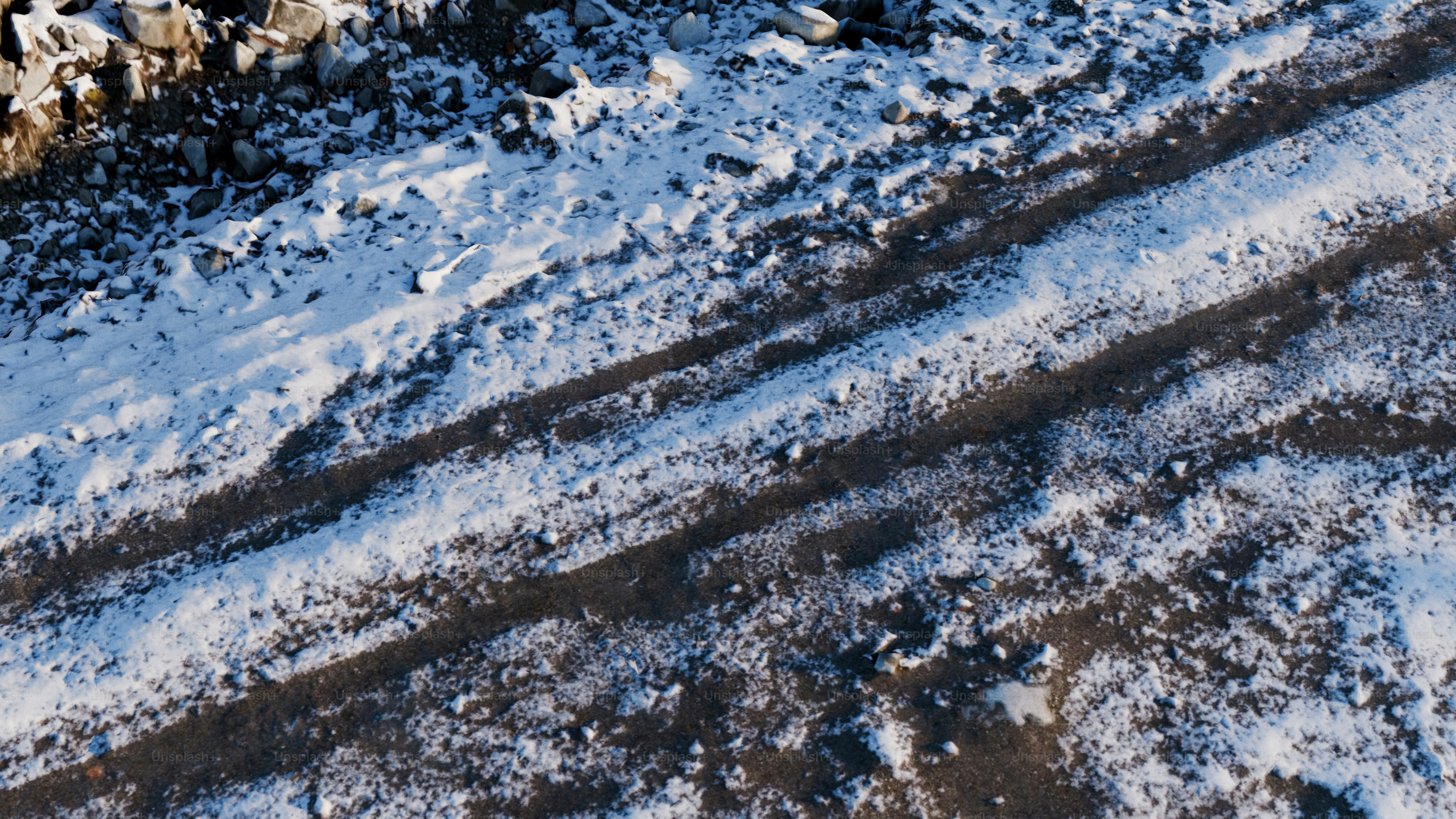 Trilhas nevadas em uma superfície escura e áspera.
